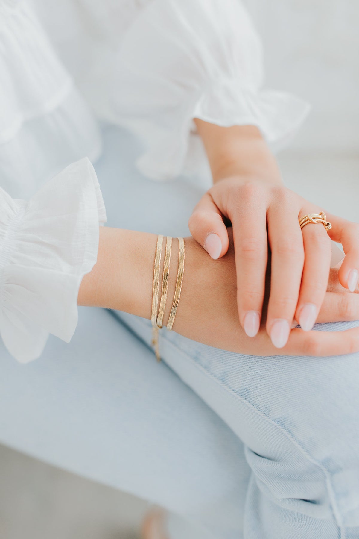 Styled view of the gold herringbone bracelet draped on a wrist, highlighting the smooth profile and comfortable, lightweight fit.