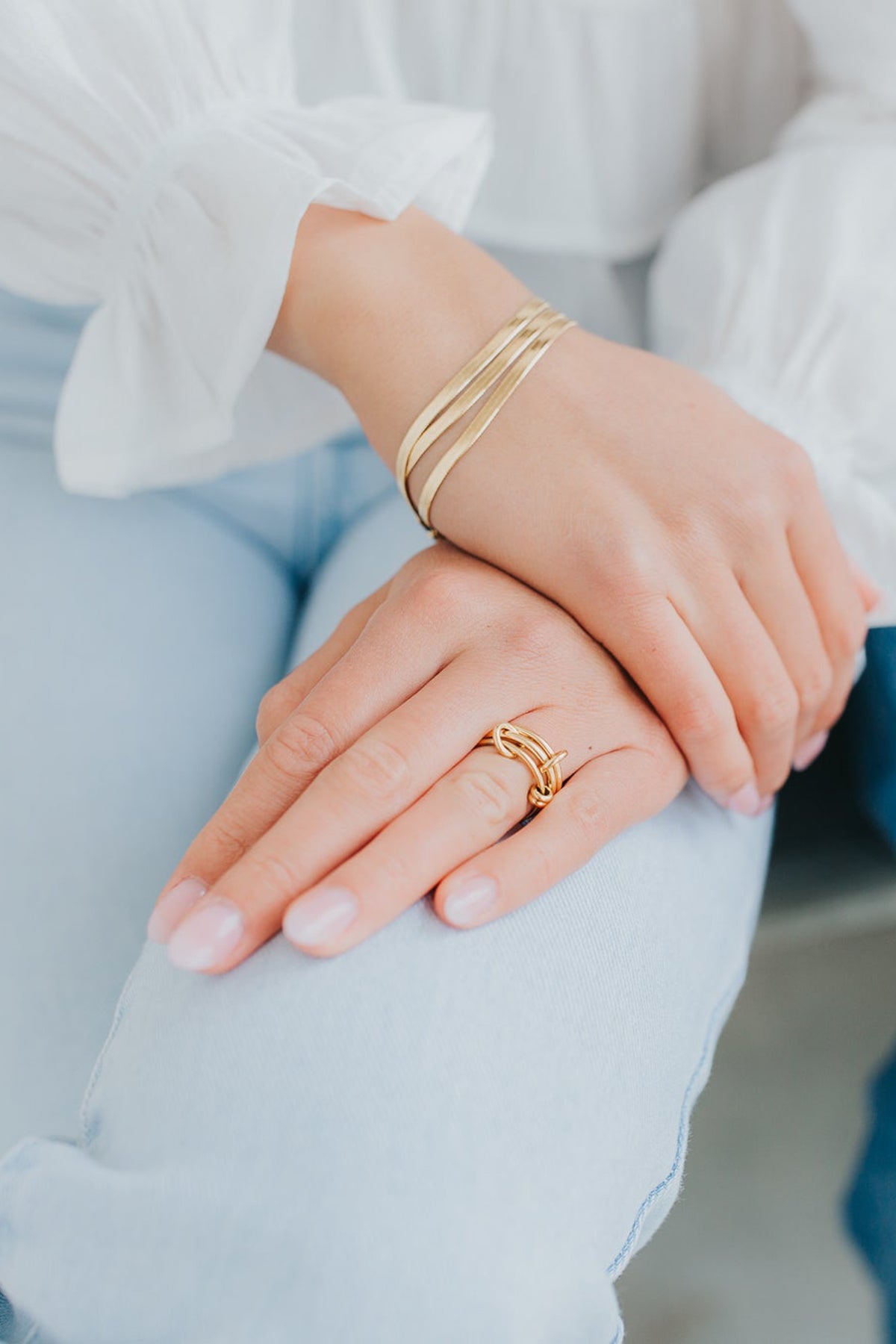 Studio image of the gold herringbone bracelet on a neutral background emphasizing its lightweight feel and smooth, reflective surface.