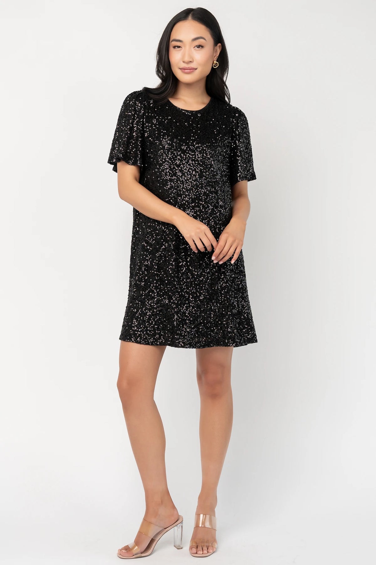 Black liquid sequin mini shift dress with a round neckline, short flutter sleeves, and a satin bow back detail.