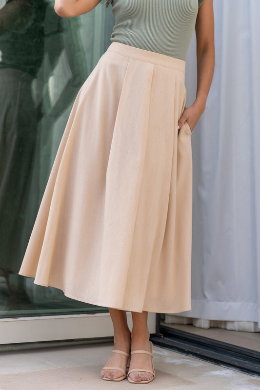 Studio front view of natural-colored pleated midi skirt showing high-rise waistband, crisp pleats and smooth, fully lined interior.