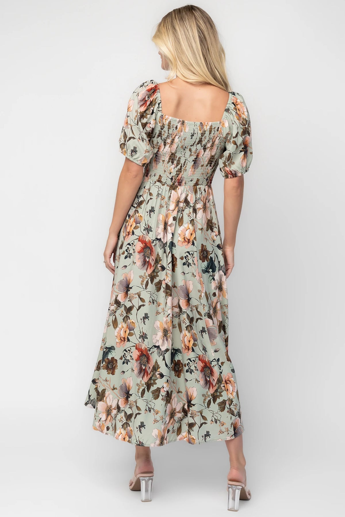 Model wearing the Charlotte Midi Dress in Sage, a sage green midi dress with a pink multi floral print, rounded square neckline, puff sleeves, banded waist, and flowing A-line skirt with side pockets.