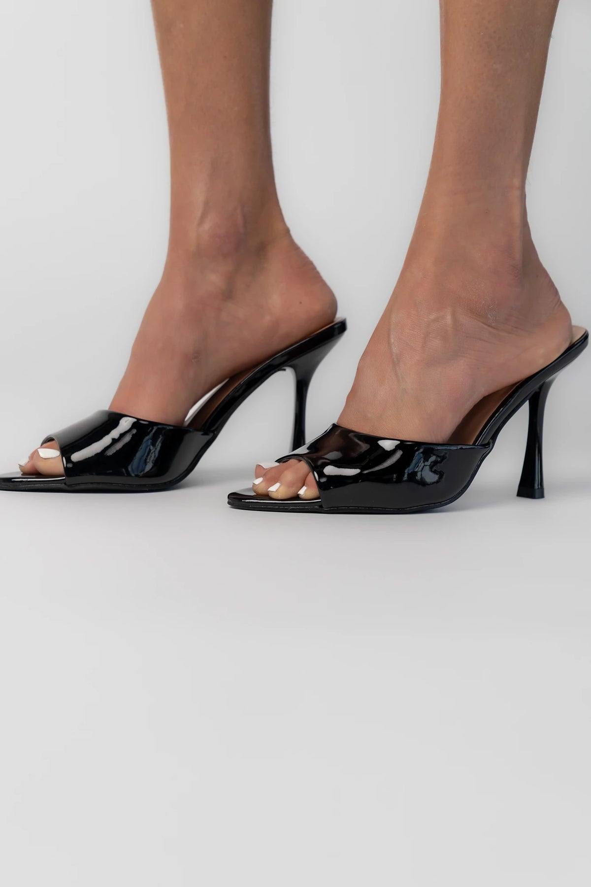 Black patent mule heels with an open toe, slip-on design, and block heel.