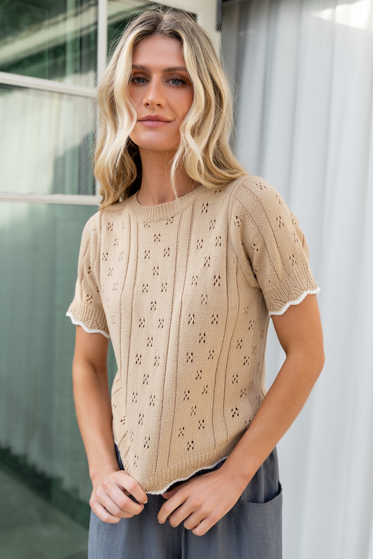 Back view of model wearing Britt Pointelle Knit Top, Natural + Ivory, showing ribbed neckline and hem with delicate pointelle knit texture.