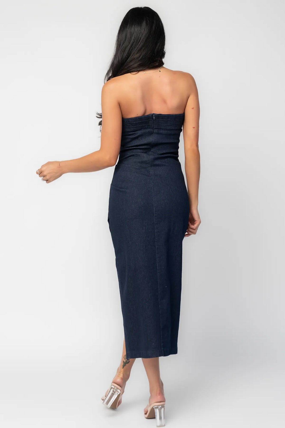 Back view of model showcasing the Caldwell Denim Midi Dress in Dark Wash, strapless dark navy denim midi dress with a pleated bust