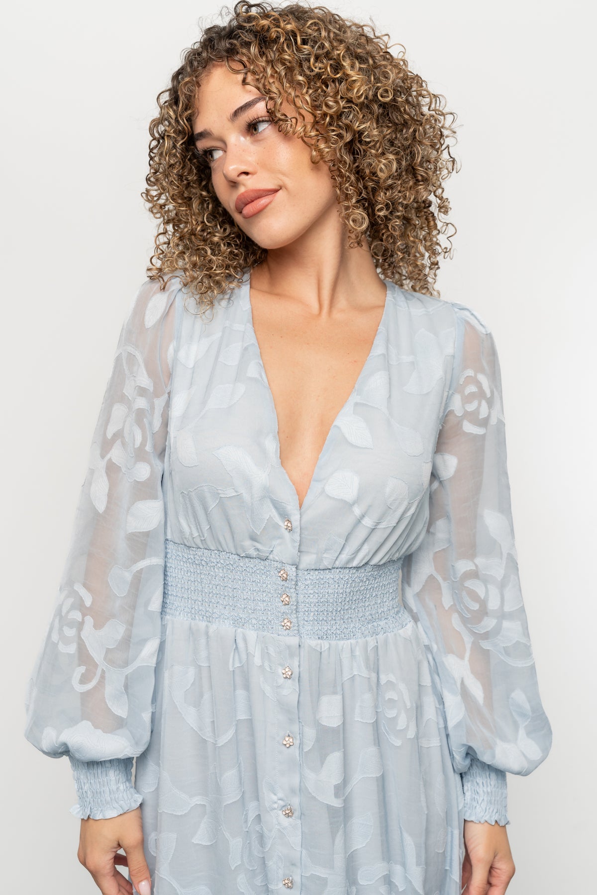Close-up detail of functional flower buttons and delicate burnout floral texture on the light blue Daniella chiffon dress bodice.
