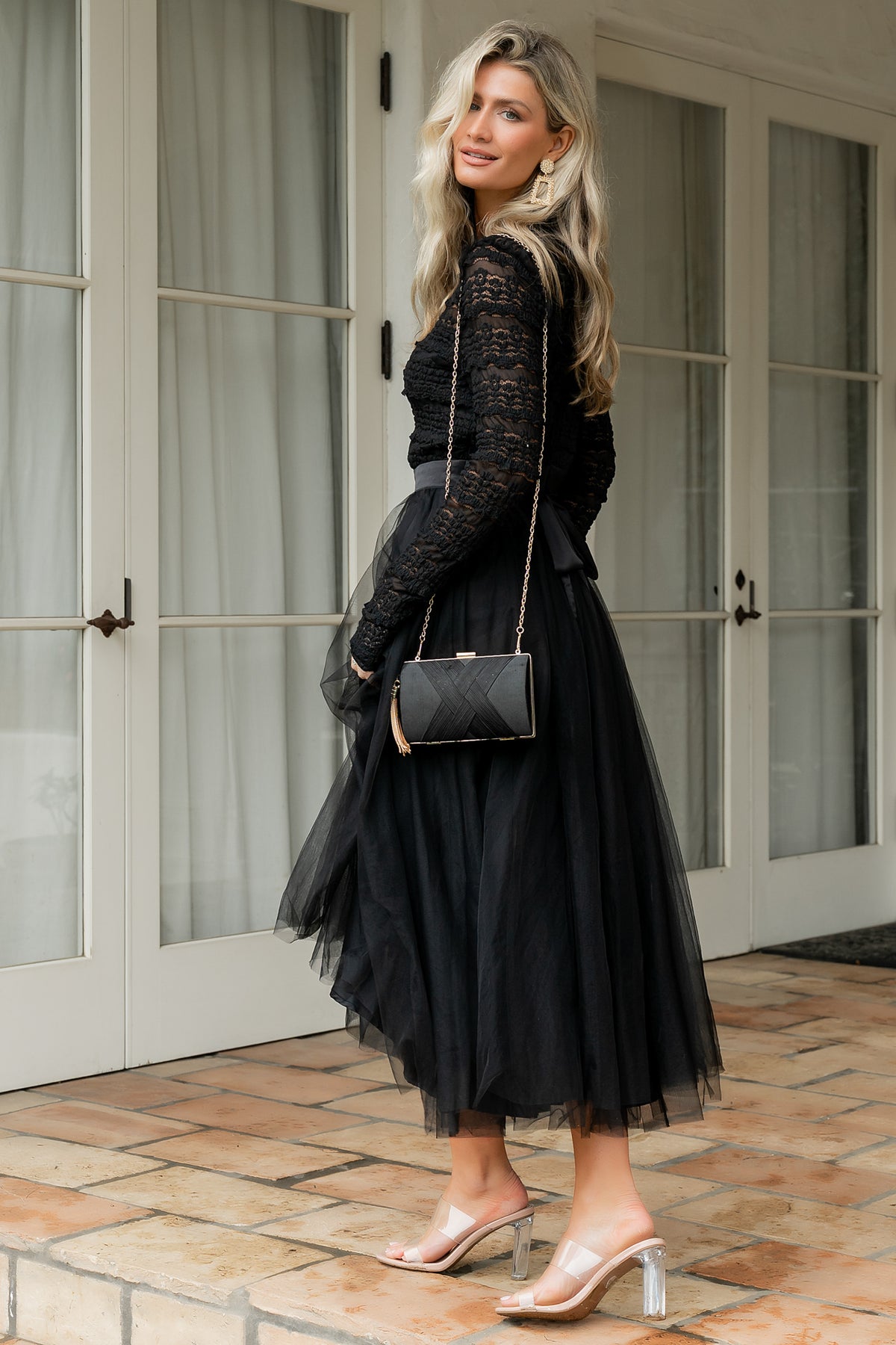 Side view of the Lonnie Tulle Dress in black highlighting the long lace sleeve with elastic cuff and the dress's layered tulle silhouette in motion.