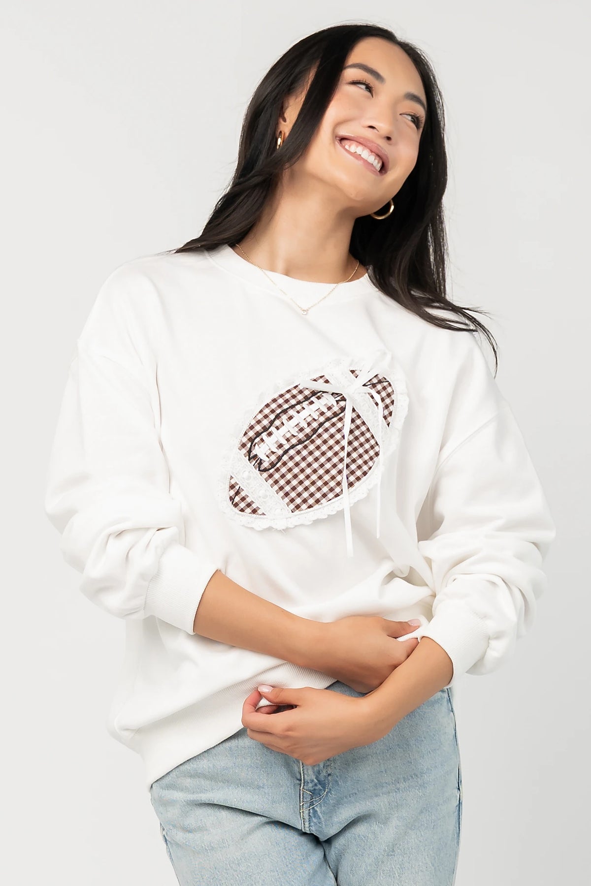 Stephen Gingham Crewneck in Ivory with brown gingham lace appliqué, ribbon bow detail, long sleeves, and ribbed trim.