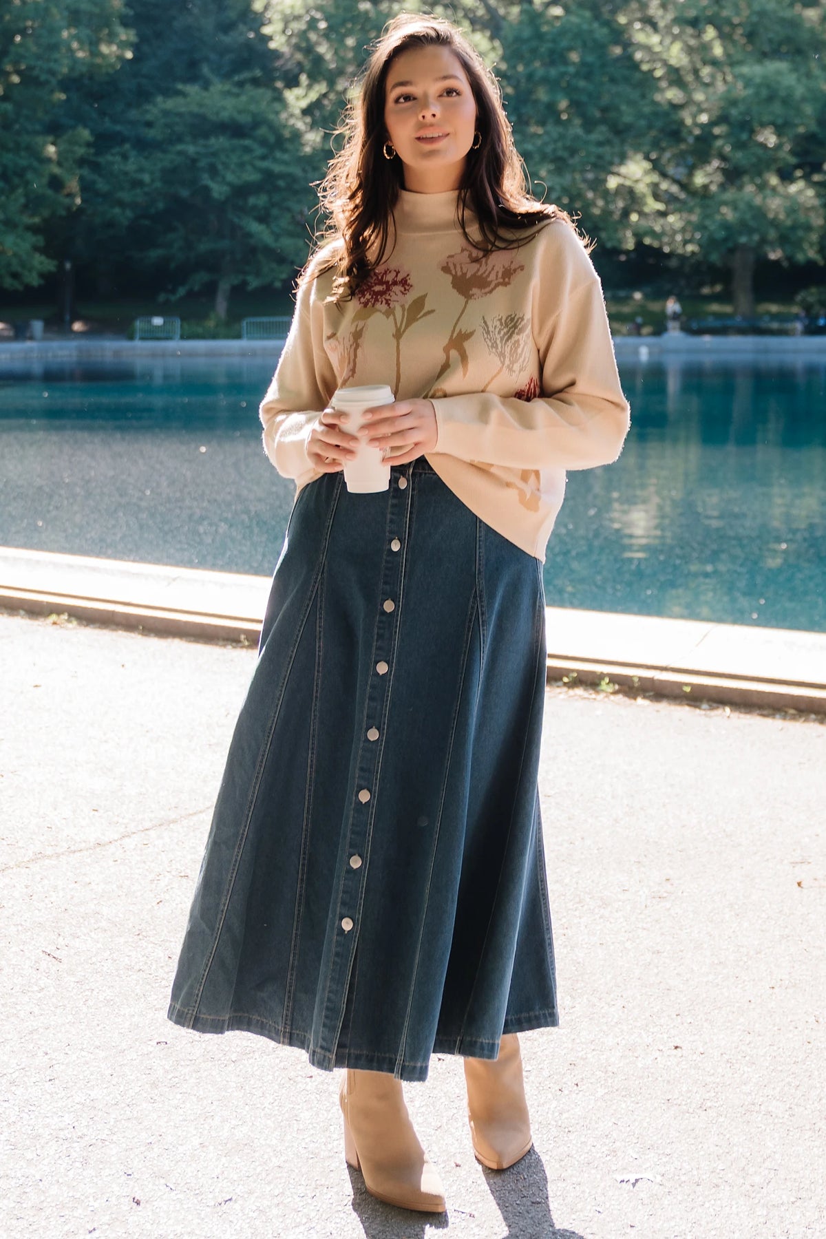 Natural knit sweater with a mock neckline, long sleeves, relaxed fit, and an embroidered floral motif at the neckline.