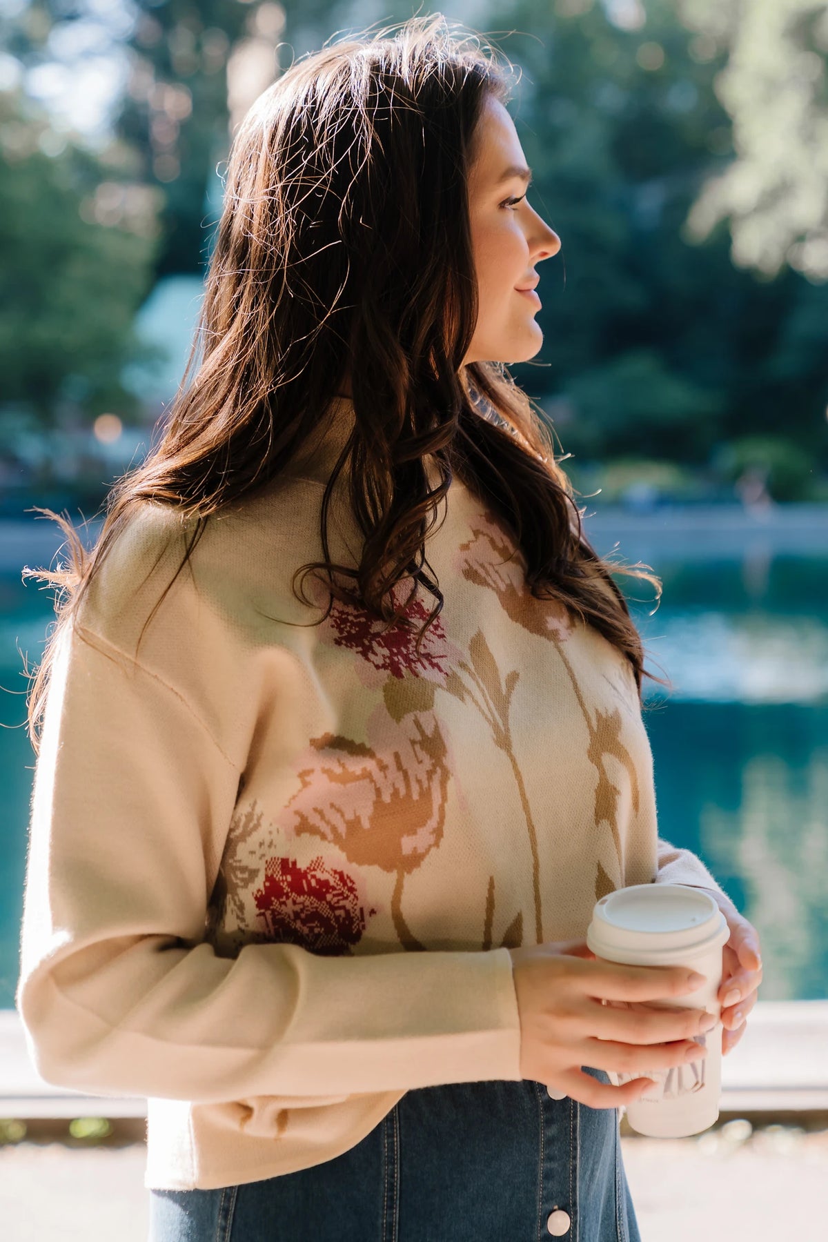 Natural knit sweater with a mock neckline, long sleeves, relaxed fit, and an embroidered floral motif at the neckline.