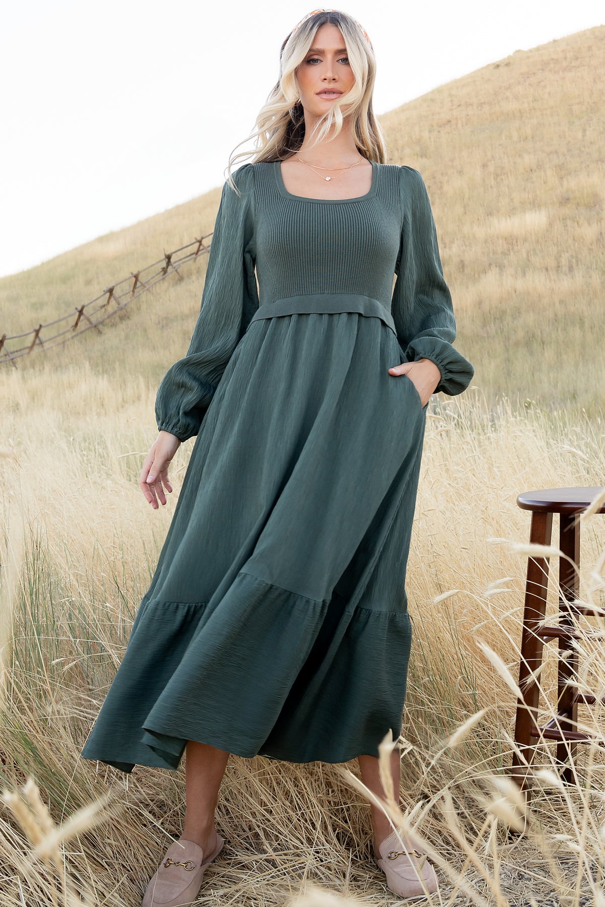 Side view of model in two-tone Alva Sweater Dress showing single-tiered midi skirt movement, mid-length hem, and discreet side pockets.
