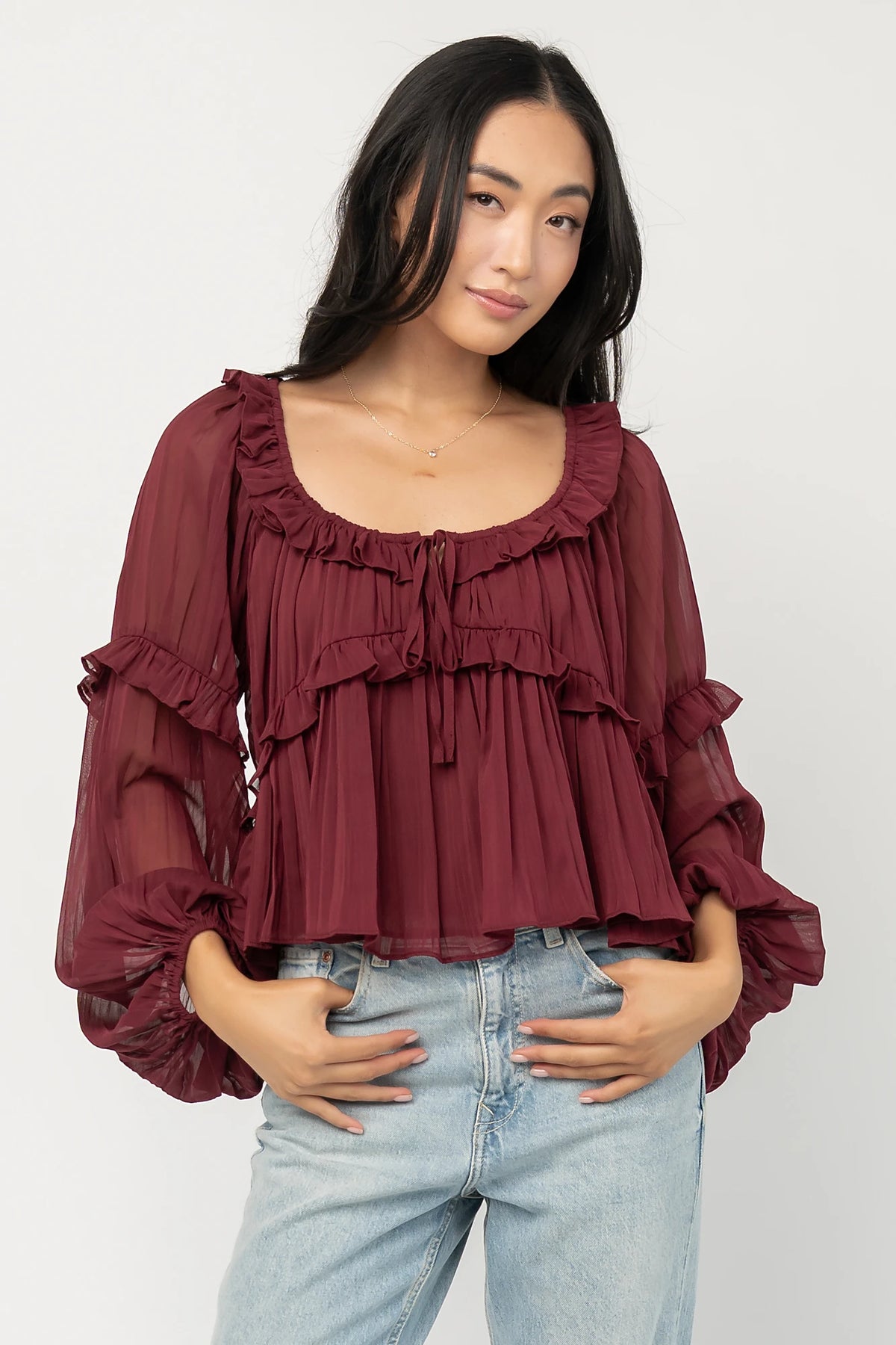Bellerose Ruffle Top in Burgundy with pleated chiffon, ruffle-trimmed neckline, front tie, and billowy long sleeves.