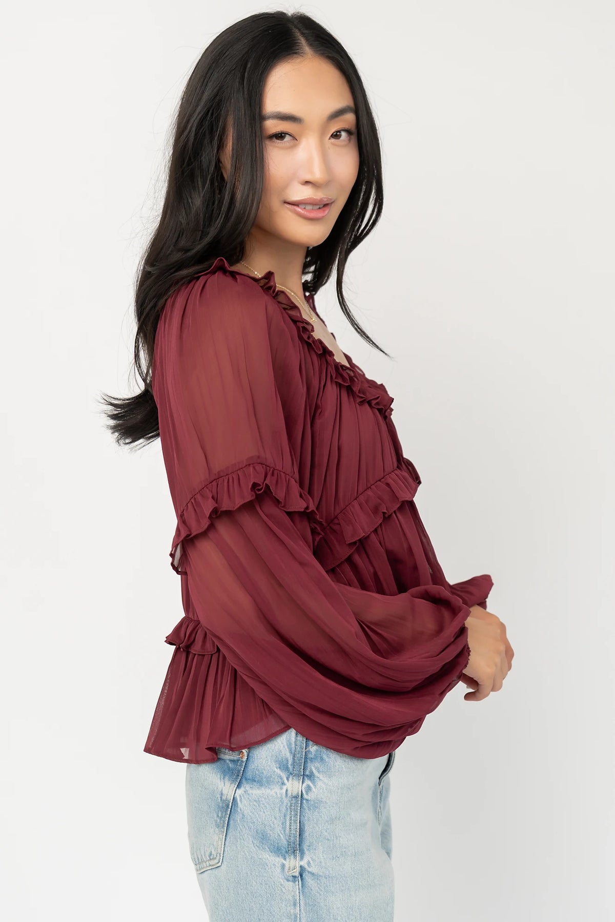 Bellerose Ruffle Top in Burgundy with pleated chiffon, ruffle-trimmed neckline, front tie, and billowy long sleeves.