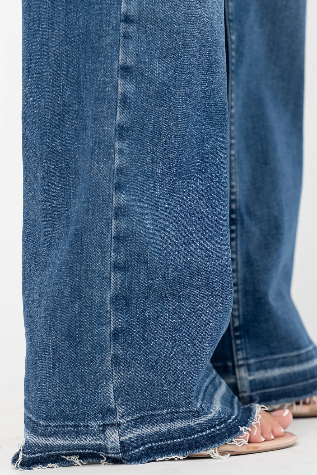 Bria High Rise Wide Leg Jeans in Medium Wash with relaxed wide legs, front and back pockets, button closure, and raw hem.