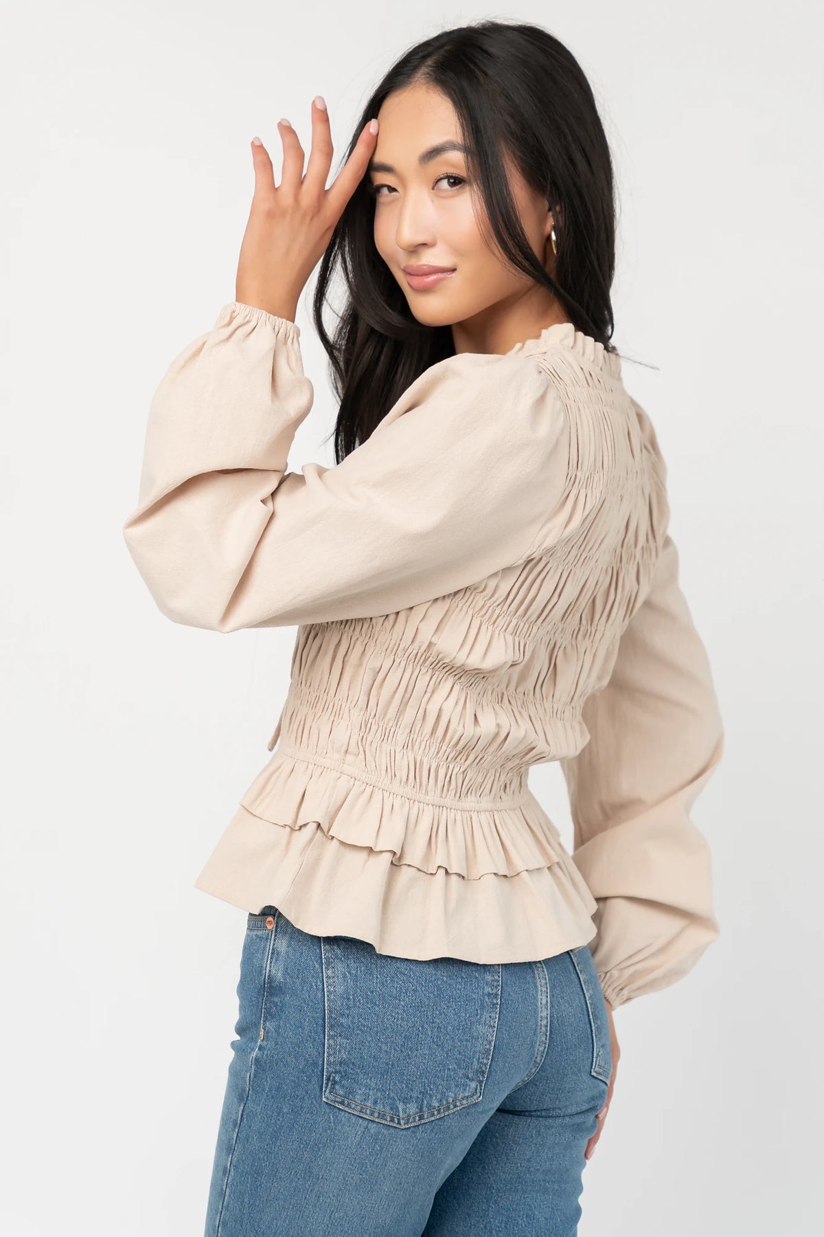 Marnie Smocked Top in Natural with smocked bodice, front bow ties, long sleeves, elastic cuffs, and peplum hem.