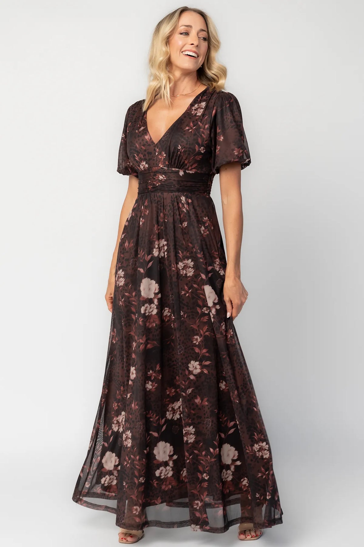 Model wearing a clove floral maxi dress with a deep V-neckline, short sleeves, and an empire waist.