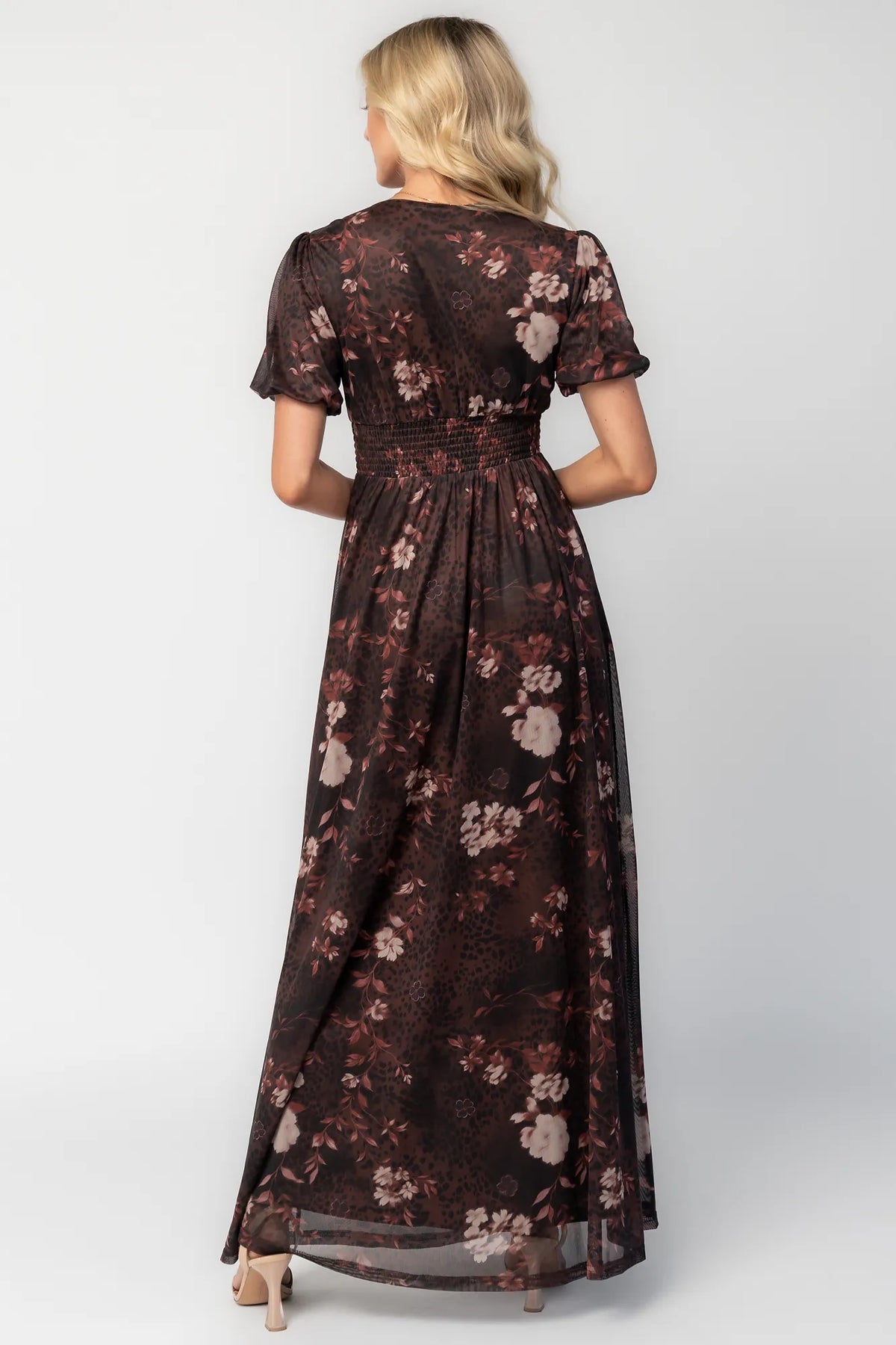 Model wearing a clove floral maxi dress with a deep V-neckline, short sleeves, and an empire waist.