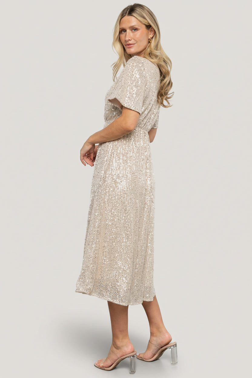 Model styled for evening with minimal jewelry and heels, showing how the champagne sequin midi dresses for celebrations.