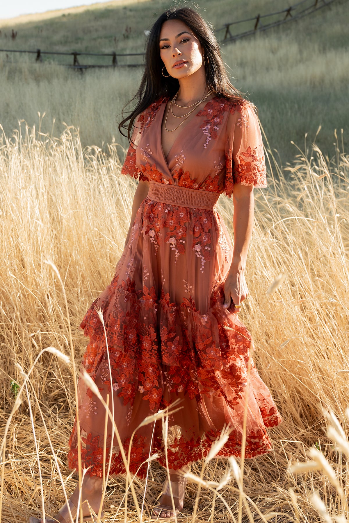 Full-length front view of model wearing the Lotte rust embroidered tulle midi dress showing crossover V-neck and floral embroidery.