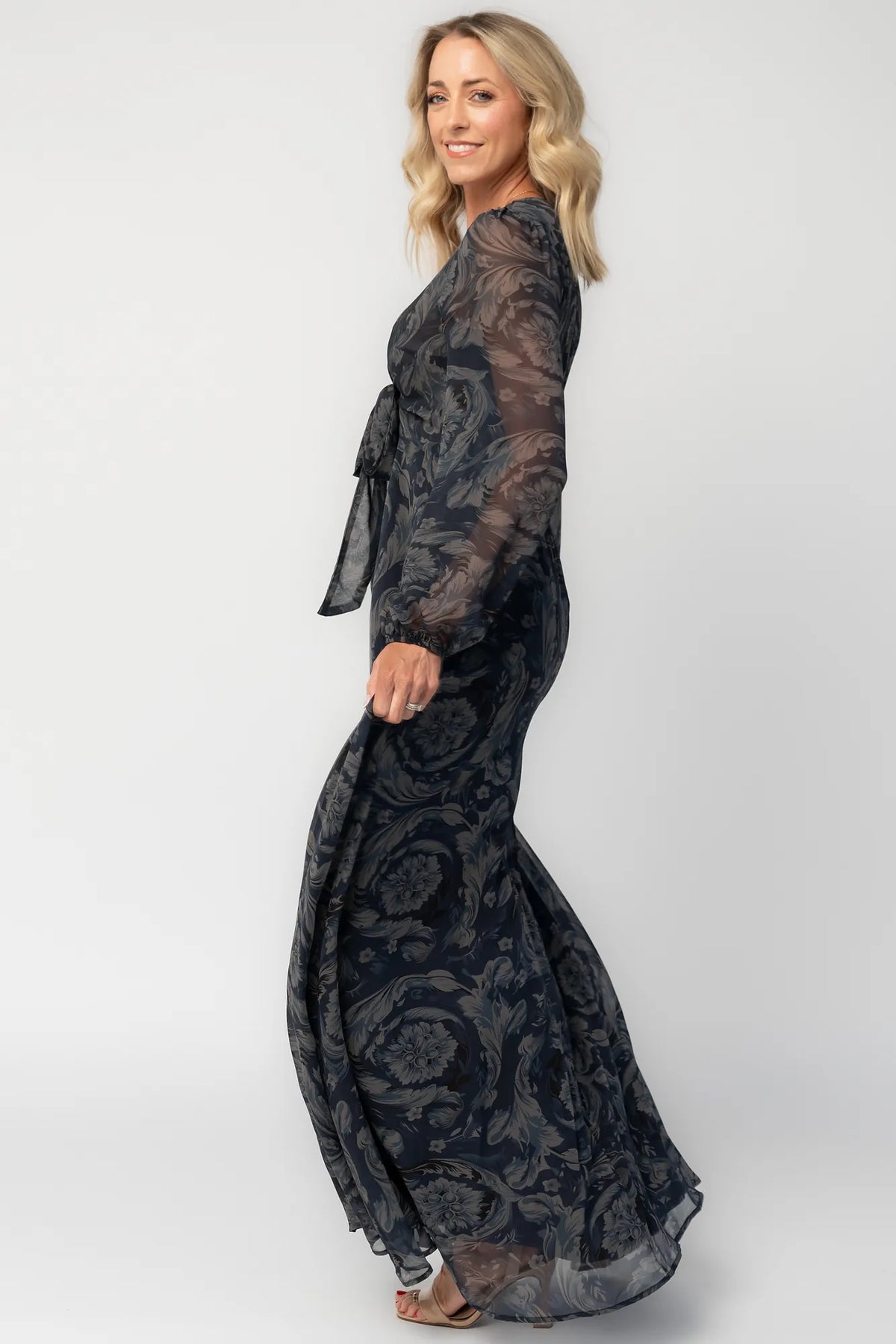 Model wearing a midnight blue floral maxi dress with a deep V-neckline and front tie keyhole detail.