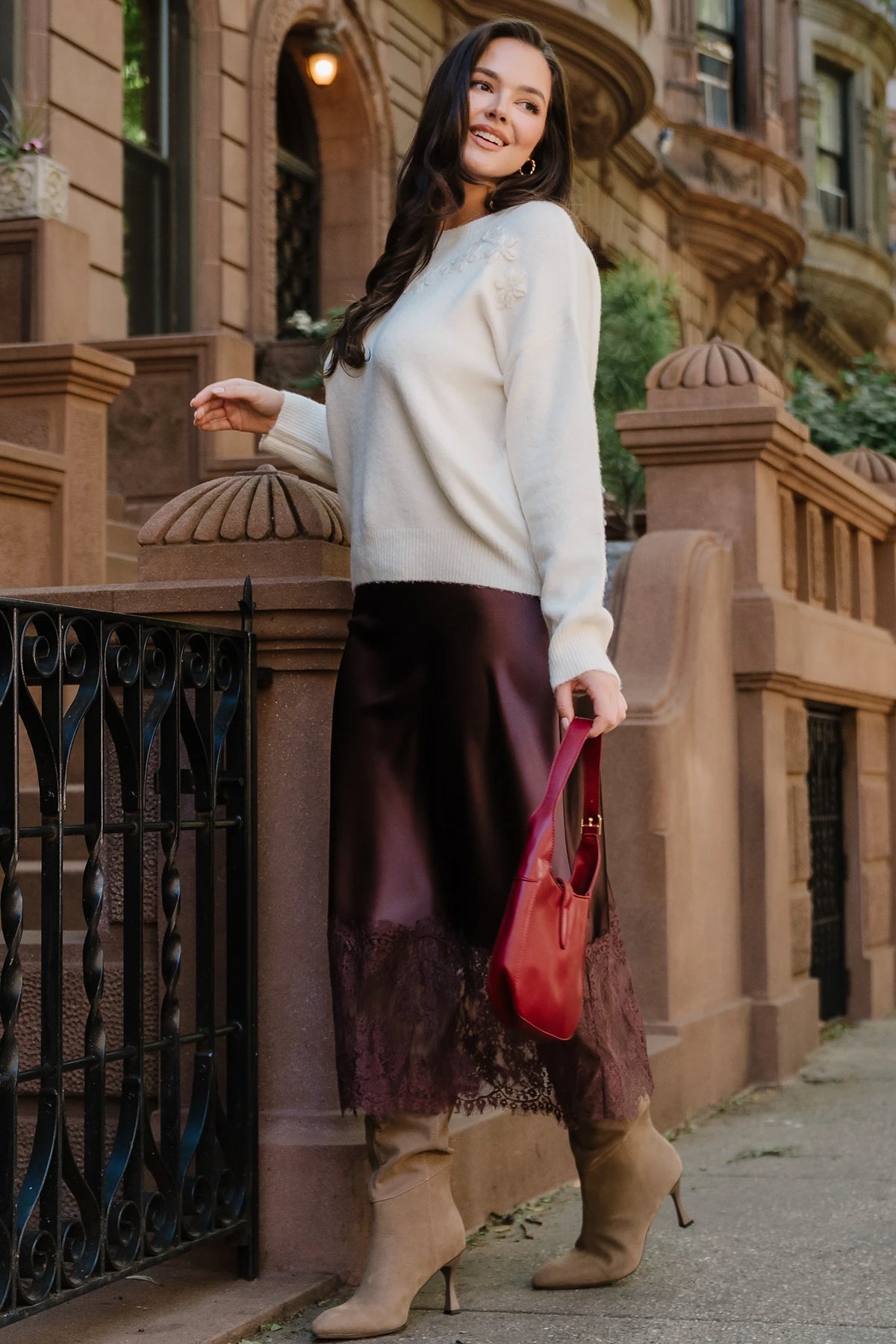 Model wearing the Kamara Satin Lace Skirt in Chocolate featuring a high-rise waistband, bias-cut satin silhouette, delicate floral lace trim at the hem, and a flowing midi length.