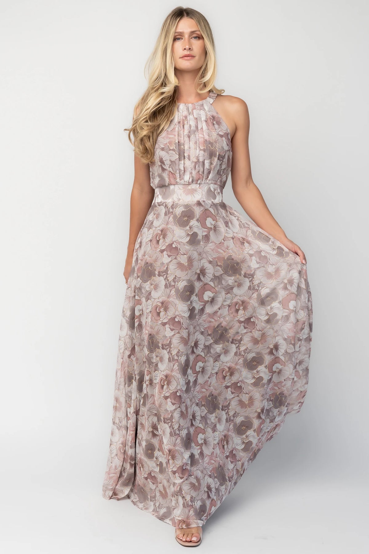 Model wearing the Tinsley Metallic Maxi Dress in Dusty Mauve featuring a high pleated halter neckline, defined waistband, tie-back keyhole detail, and a flowing chiffon maxi skirt with a dusty mauve floral print and subtle metallic shimmer.