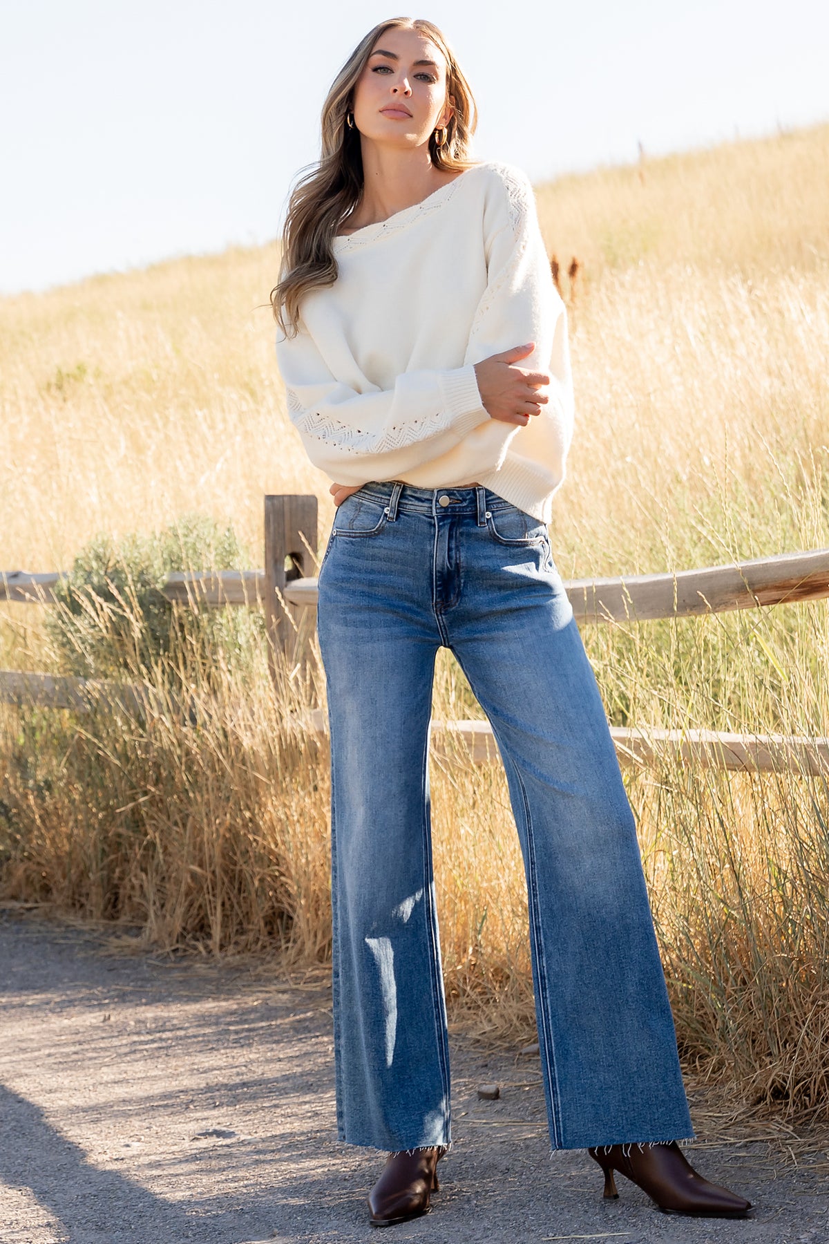 Side-angle of Noah high-rise jeans in medium wash, showing rise, fit through the hip, and ankle-length raw hem detail.
