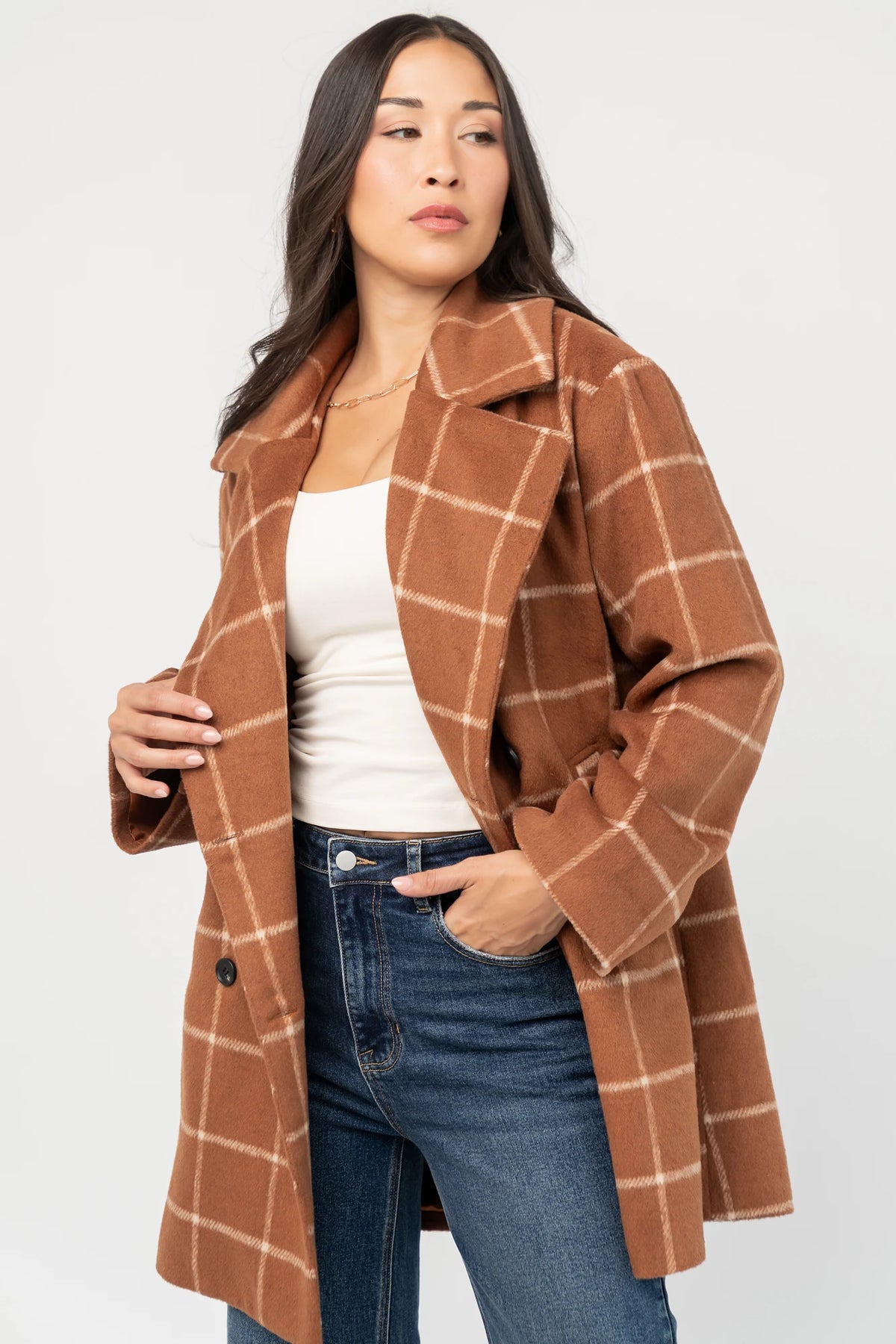 Cognac plaid mid-length coat with a cream windowpane pattern, tailored collar, button-front closure, long sleeves, front pockets, and a fully lined interior.
