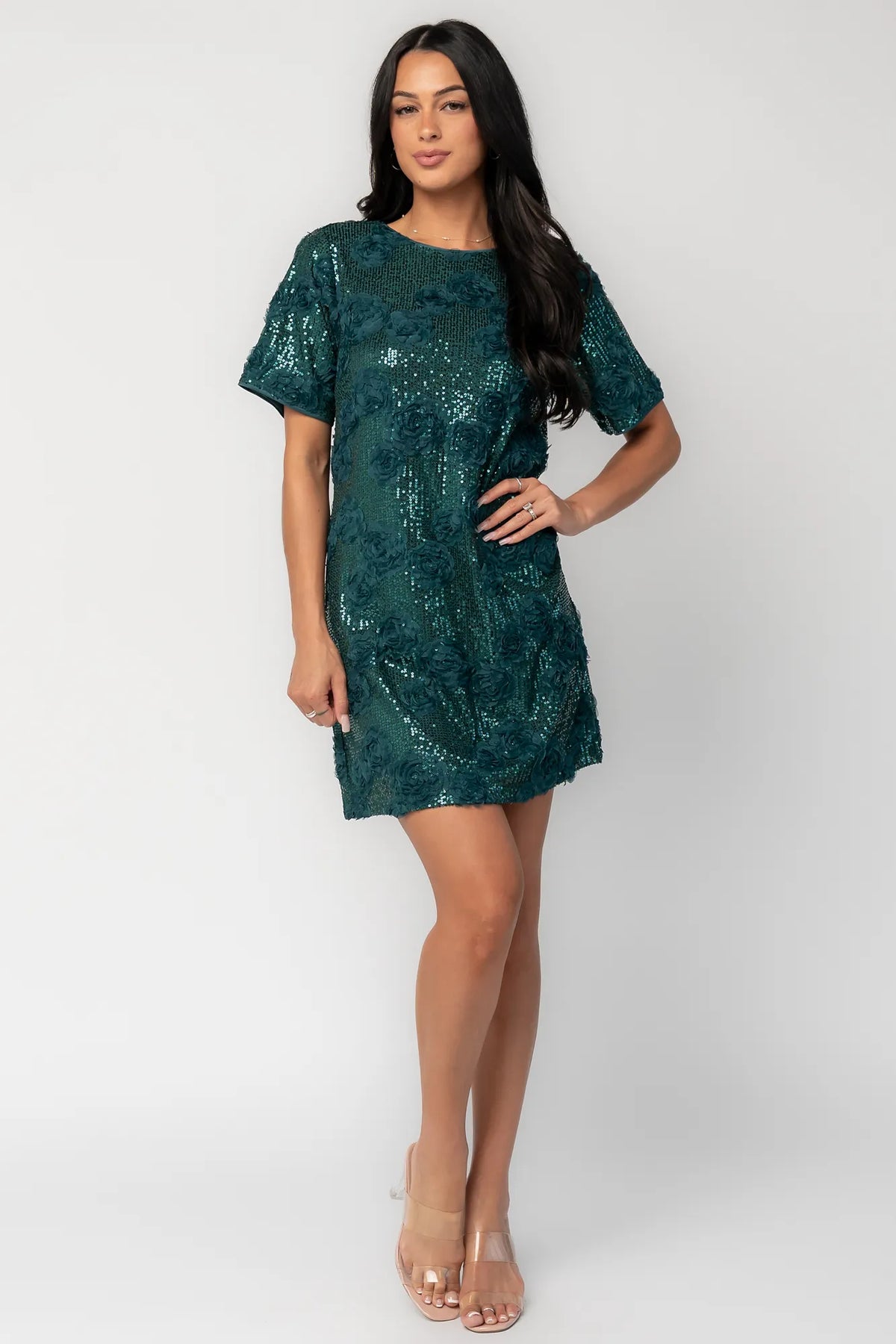 Model wearing a green short shift dress embellished with green sequins and floral appliqué detailing.
