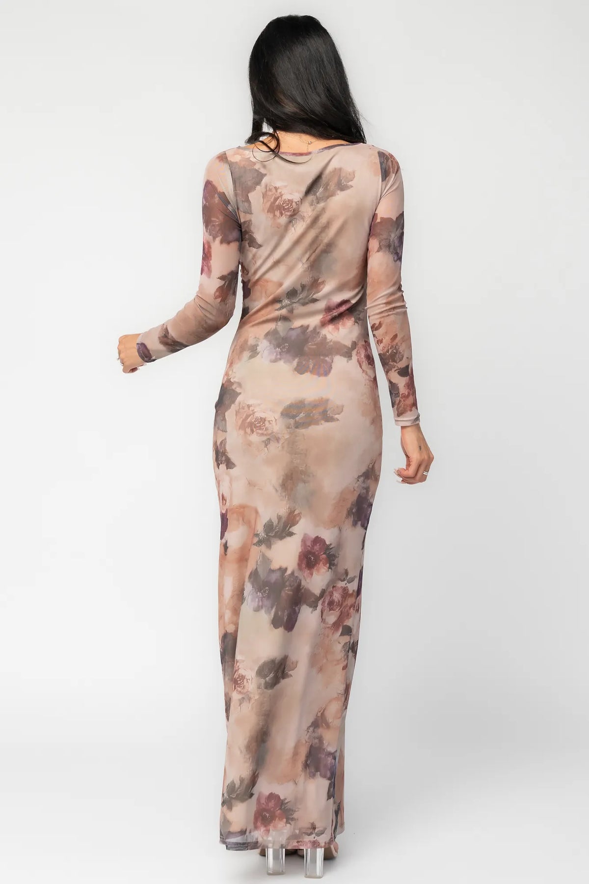 Model wearing a dark taupe floral maxi dress with a fitted bodycon silhouette, sheer long sleeves, and a round neckline.