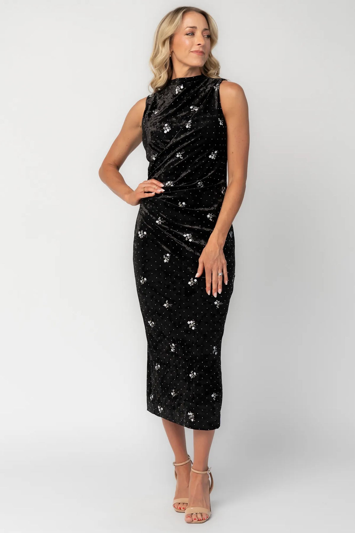 Model wearing a black velvet midi dress with a high neckline and fitted silhouette.