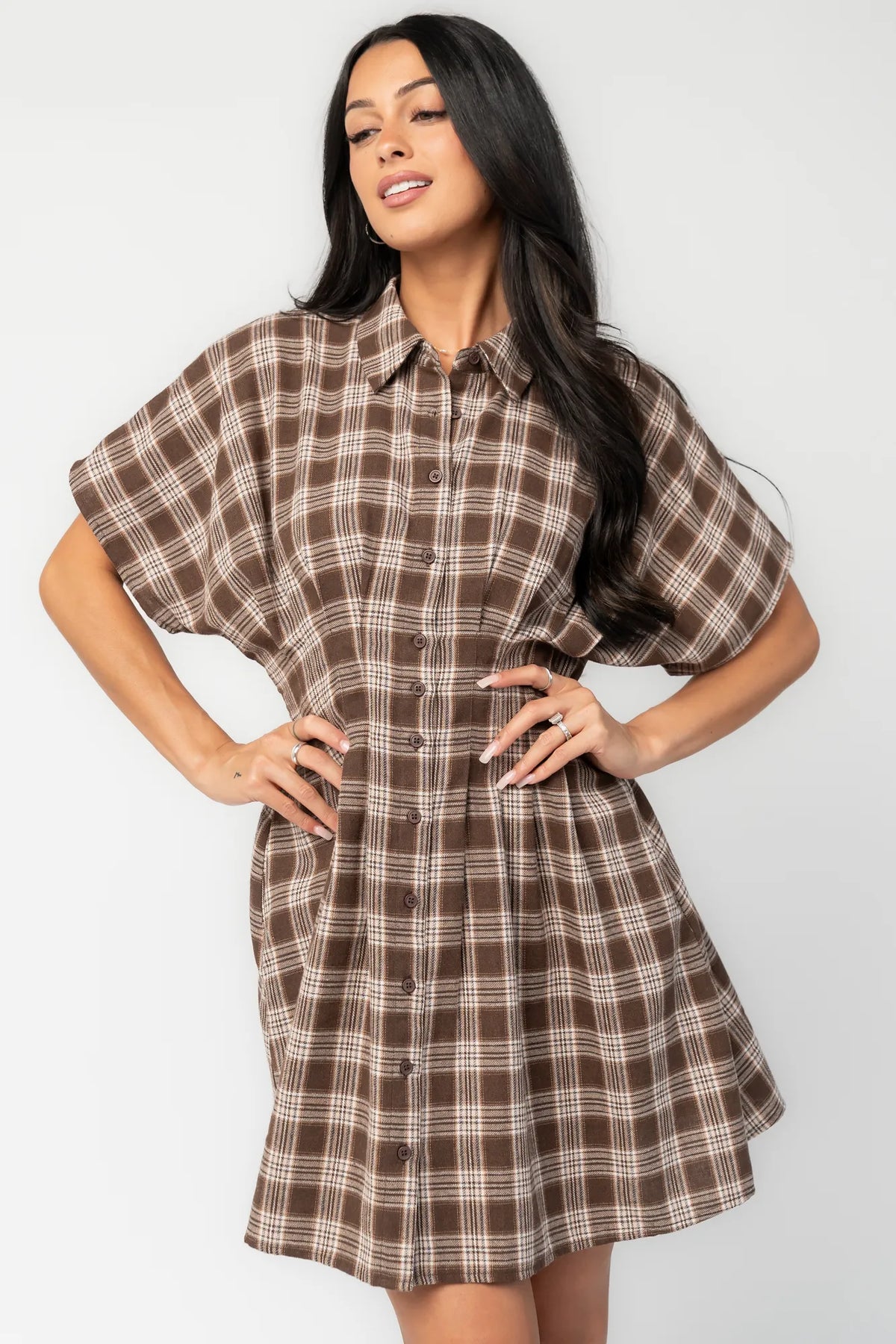Model wearing a brown plaid short dress with a collared neckline, button-front closure, and short dolman sleeves.