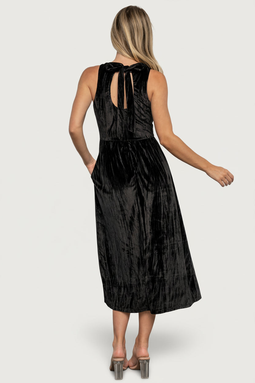 Styled look: Octavia black velvet midi paired with minimal jewelry and heels, shown in an editorial studio setting.