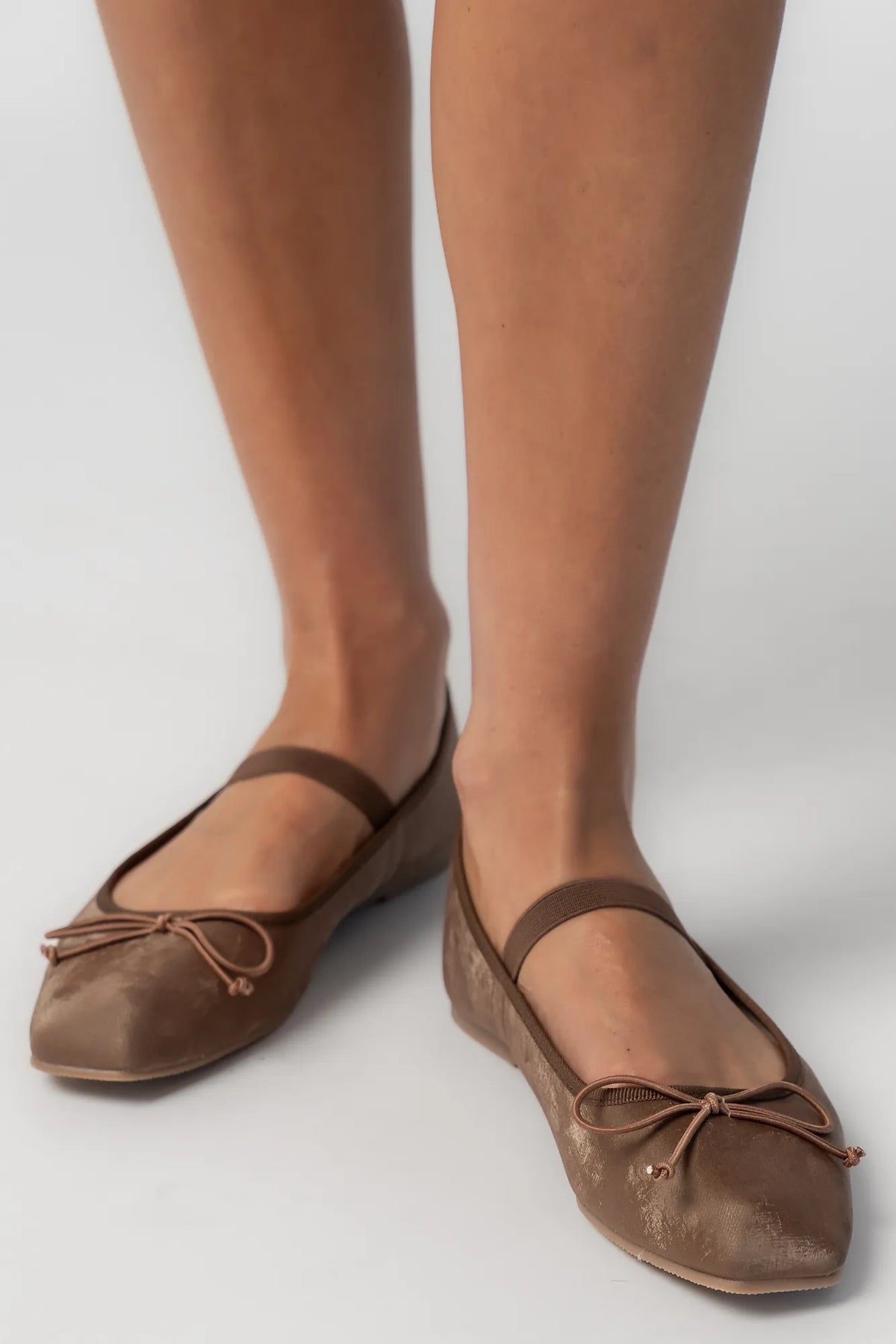 Pair of mocha velvet Mary Jane ballet flats featuring a square toe, delicate bow detail, and elastic strap across the foot. The classic flat silhouette offers a timeless, feminine look for everyday wear.