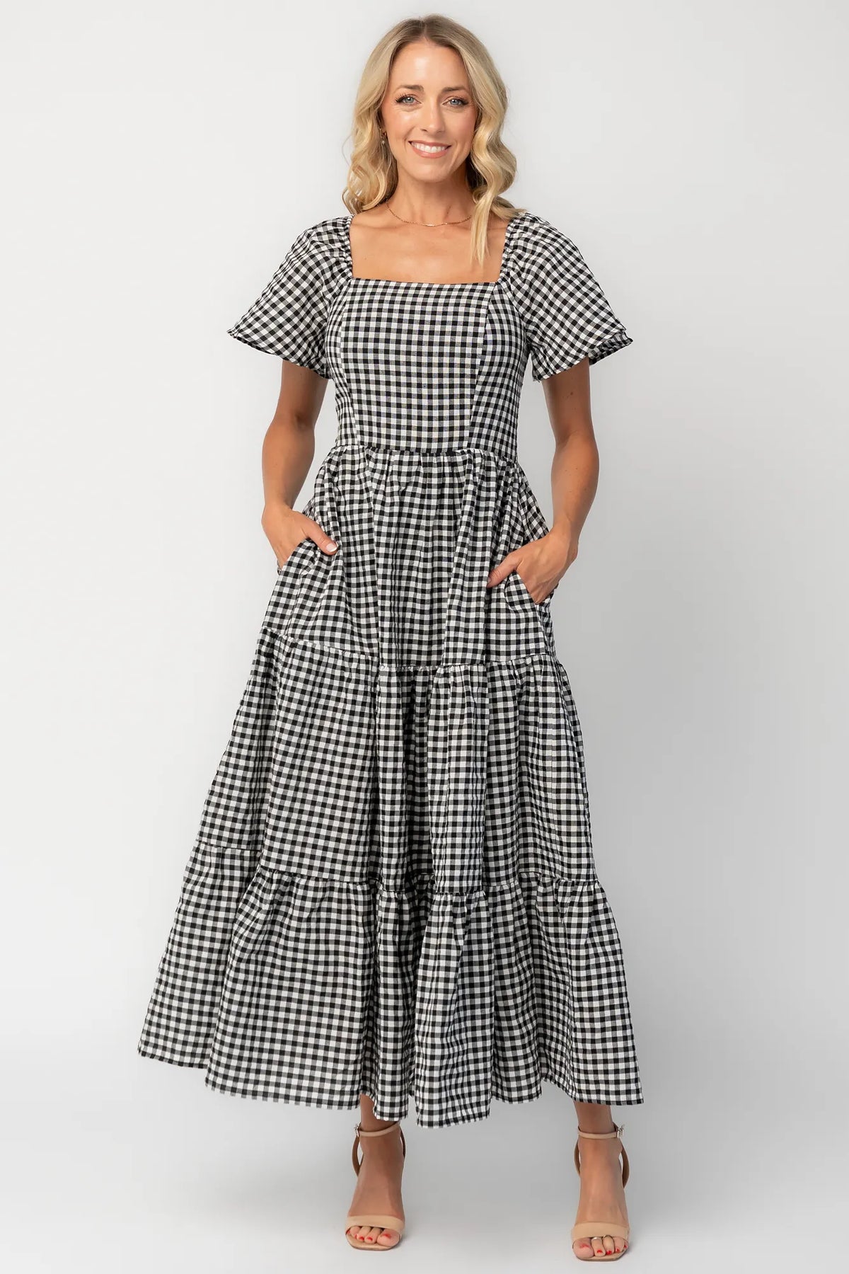 Model wearing a black and white gingham maxi dress with a square neckline, flutter sleeves, and a fitted bodice.