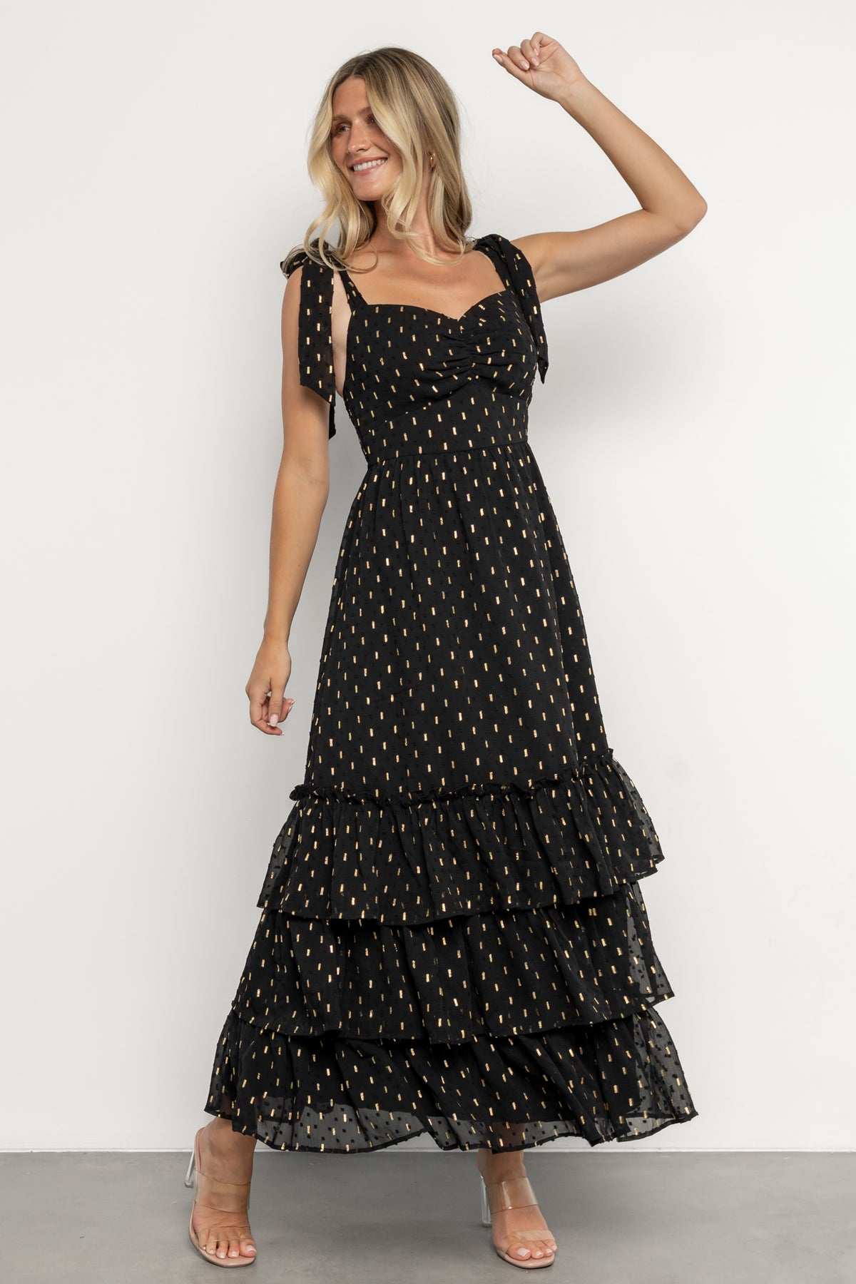 Kassia Maxi Dress in black chiffon with raised polka-dot texture, gold accents, smocked back and ruffle-tiered maxi skirt.