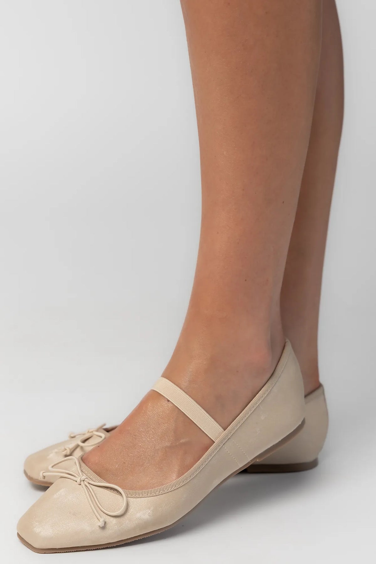 Pair of taupe velvet Mary Jane ballet flats featuring a square toe, delicate bow detail, and elastic strap across the foot. The classic flat silhouette offers a timeless, feminine look for everyday wear.