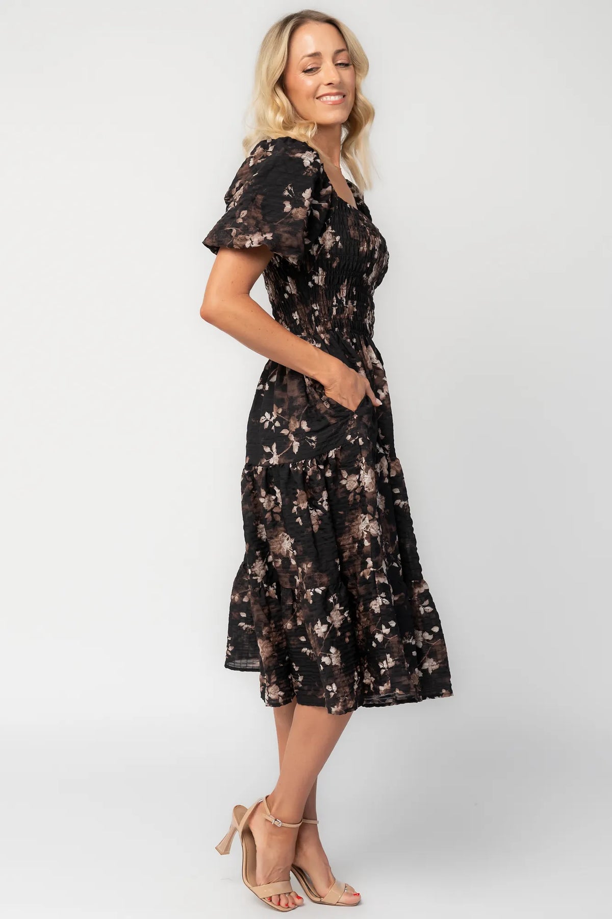 Model wearing a midi dress with a fully smocked bodice, square neckline, and short balloon sleeves.
