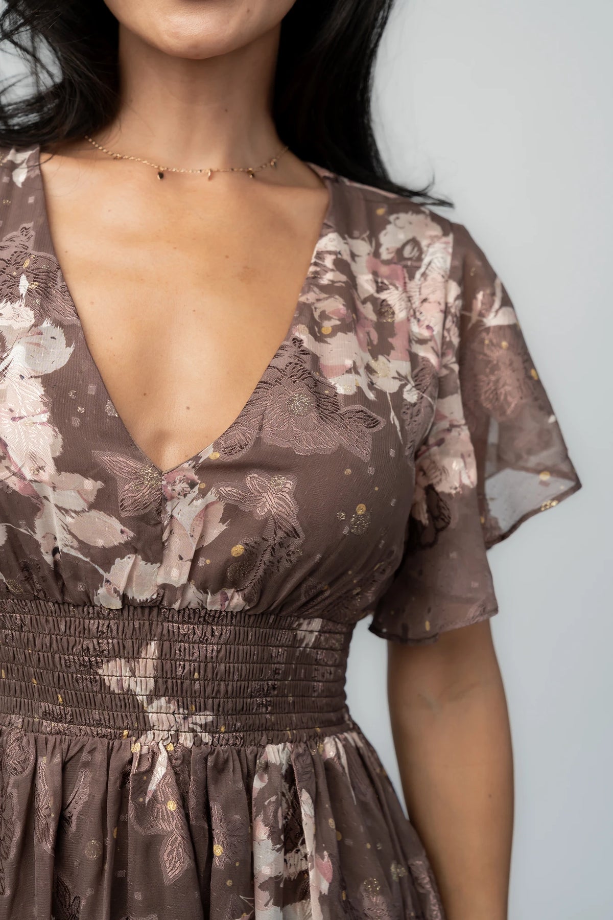 Mocha metallic floral chiffon maxi dress with a V-neckline, flutter sleeves, smocked waist, and flowing full-length skirt.