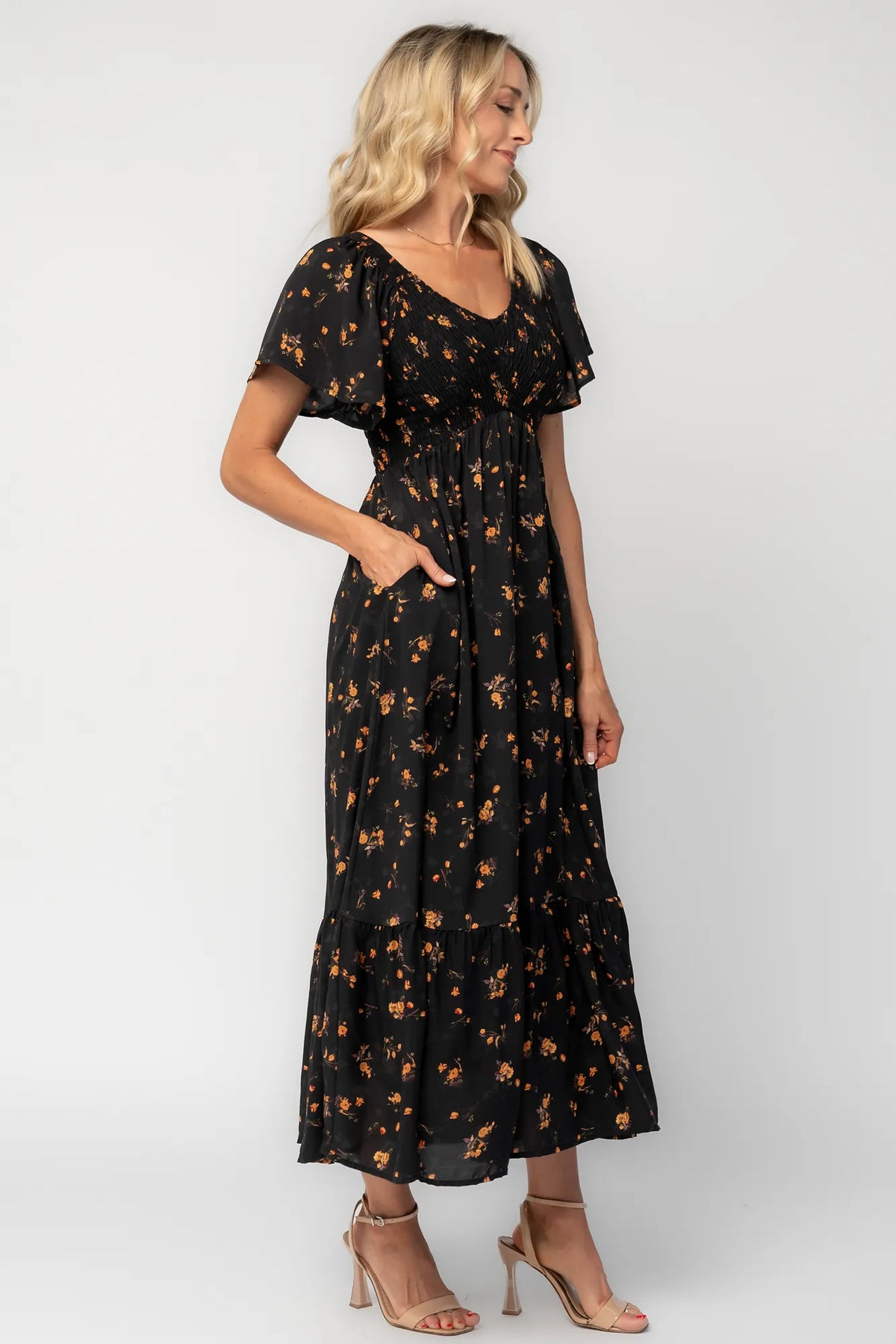 Model wearing a floral midi dress with a smocked bodice, wide V-neckline, and flutter sleeves.