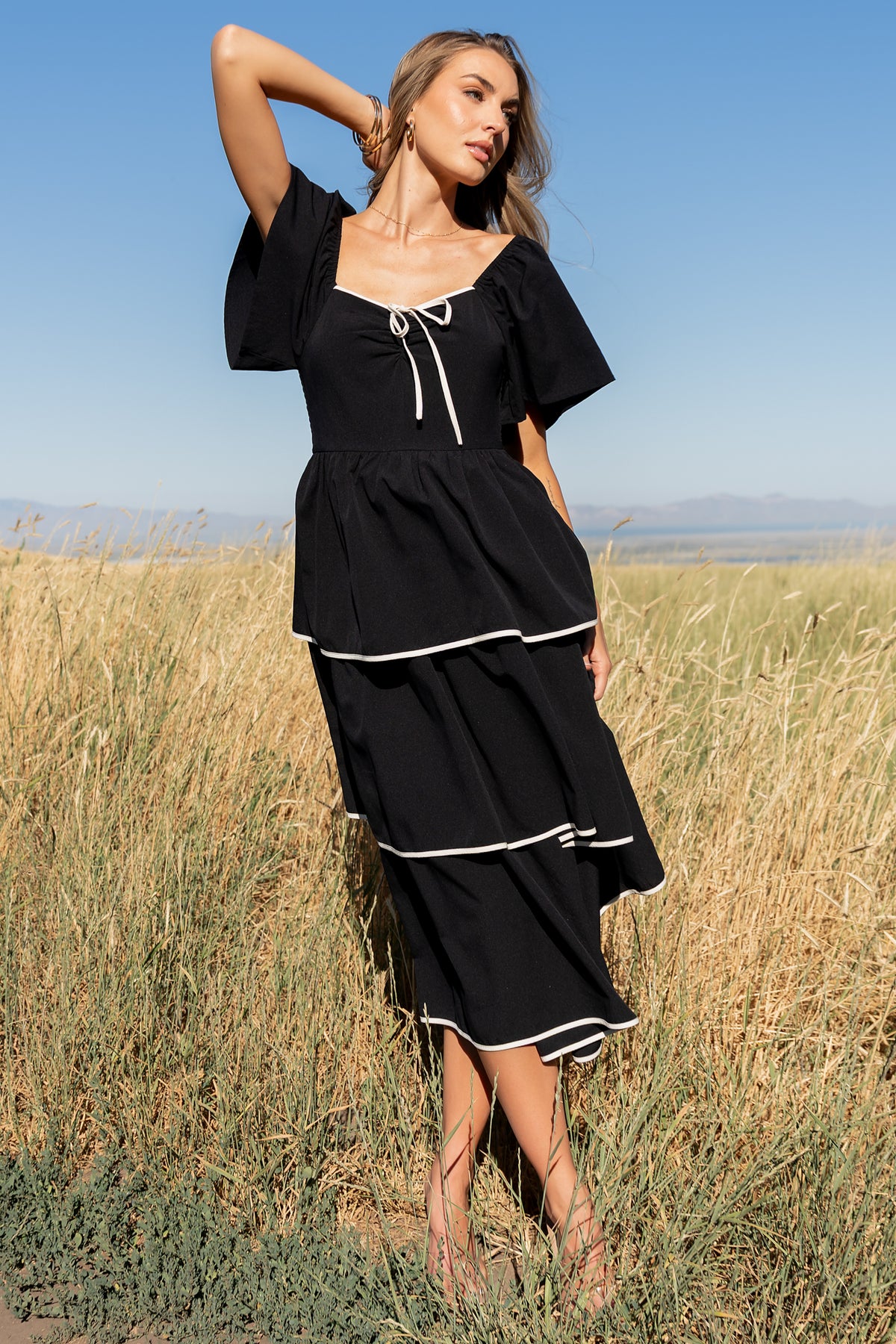 Styled outfit photo of the Madrid Tiered Midi Dress in black paired with neutral accessories to show everyday and event styling options.