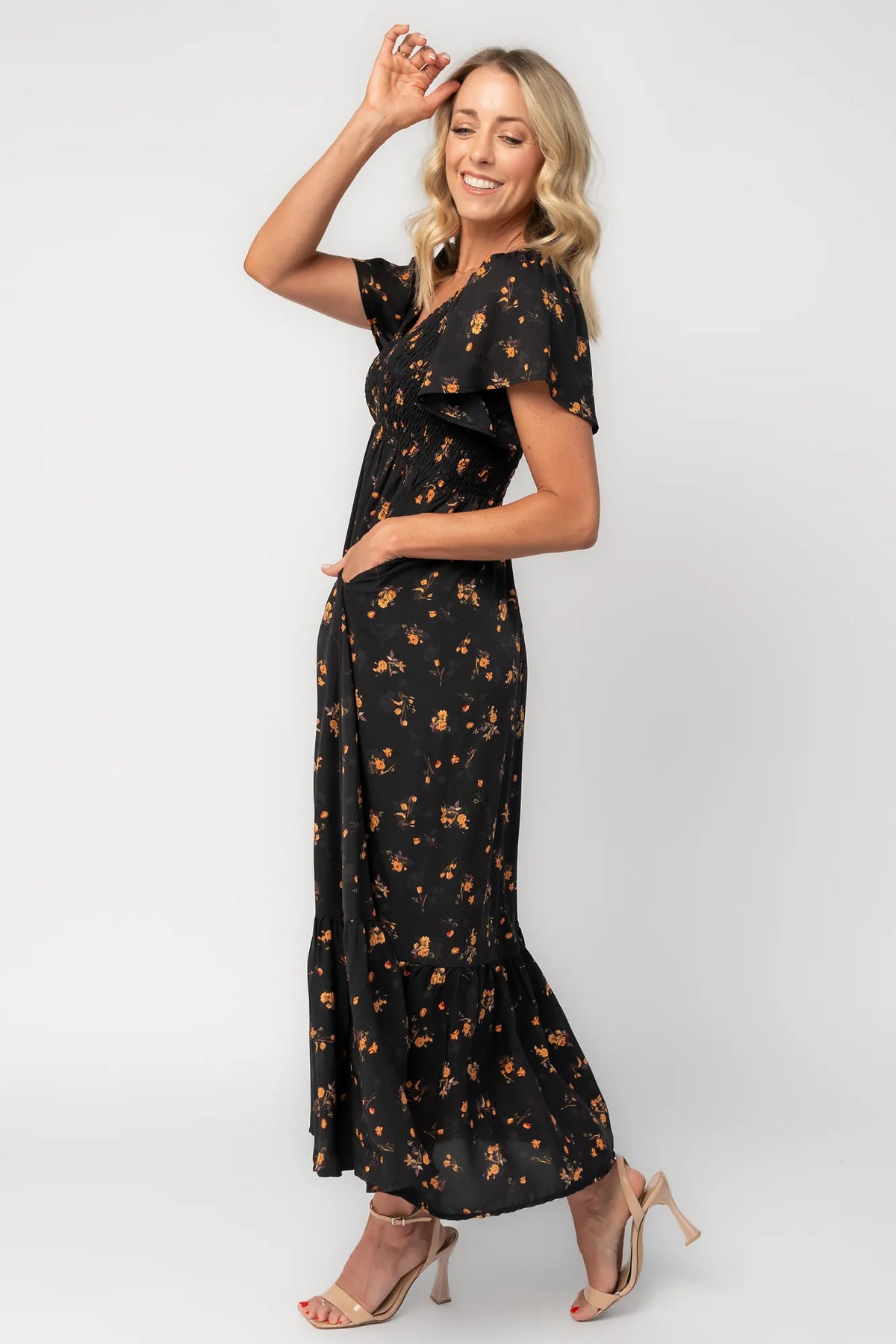 Model wearing a floral midi dress with a smocked bodice, wide V-neckline, and flutter sleeves.