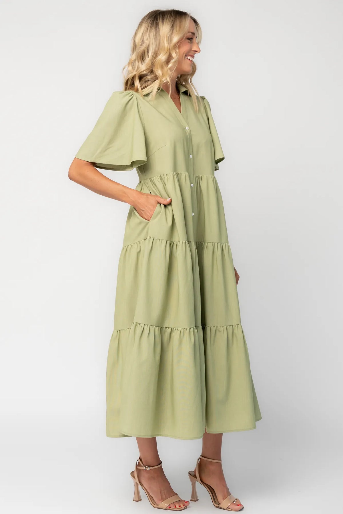 Model wearing a sage green midi dress with a collared neckline, button-front bodice, and short flutter sleeves.