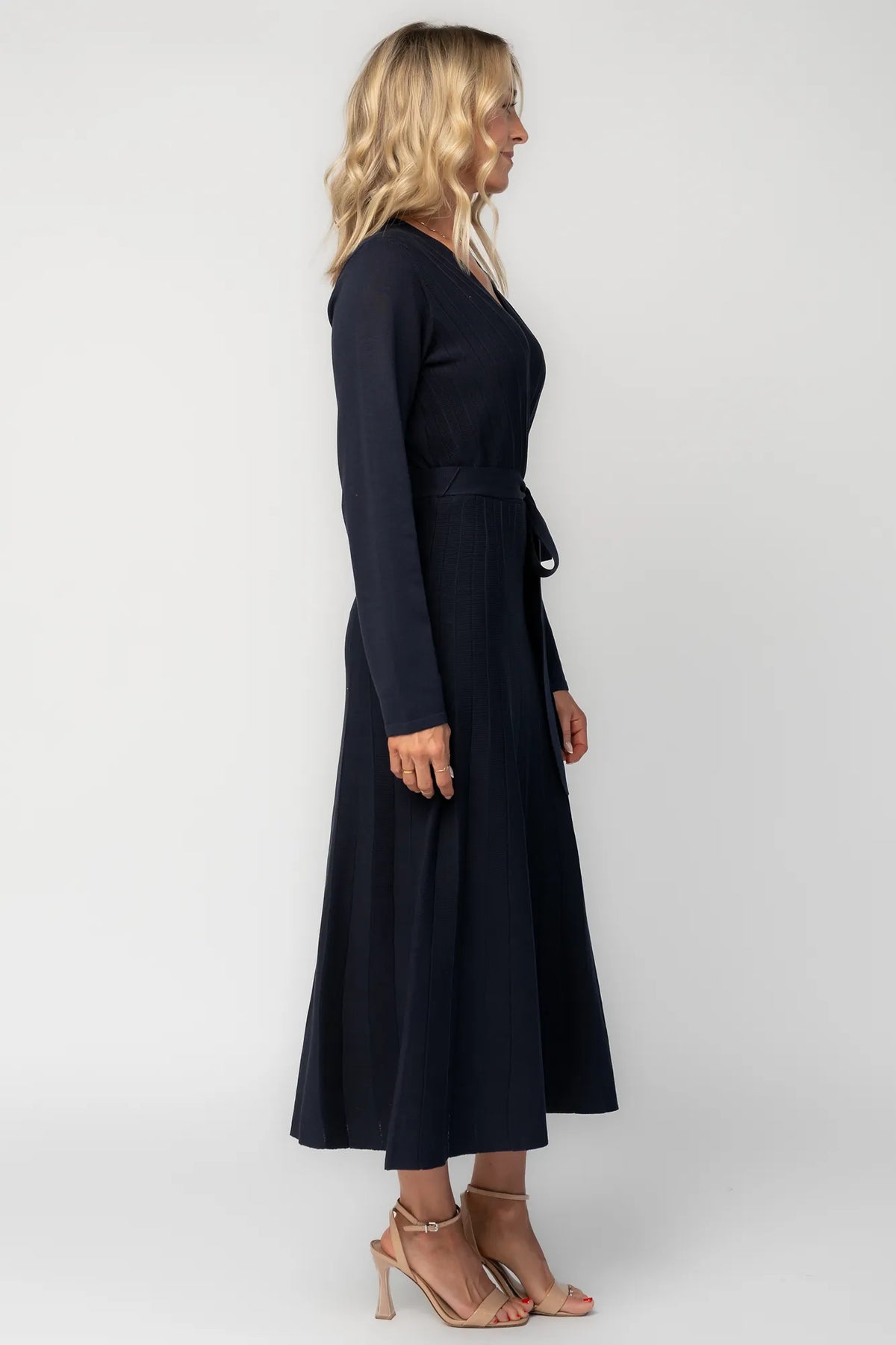 Model wearing a navy midi dress with a surplice V-neckline, long sleeves, and a matching waist tie