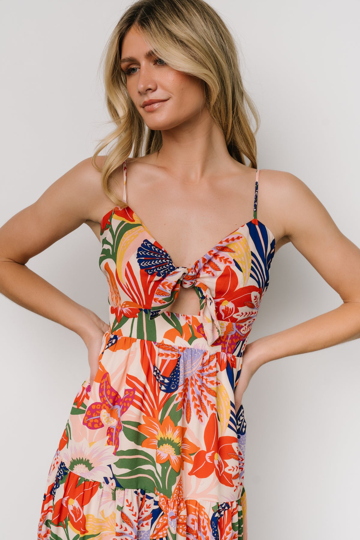 Model wearing Jaide midi dress in multi print walking pose, showing V-neckline, adjustable tie, and three-tier flow of the chiffon skirt.