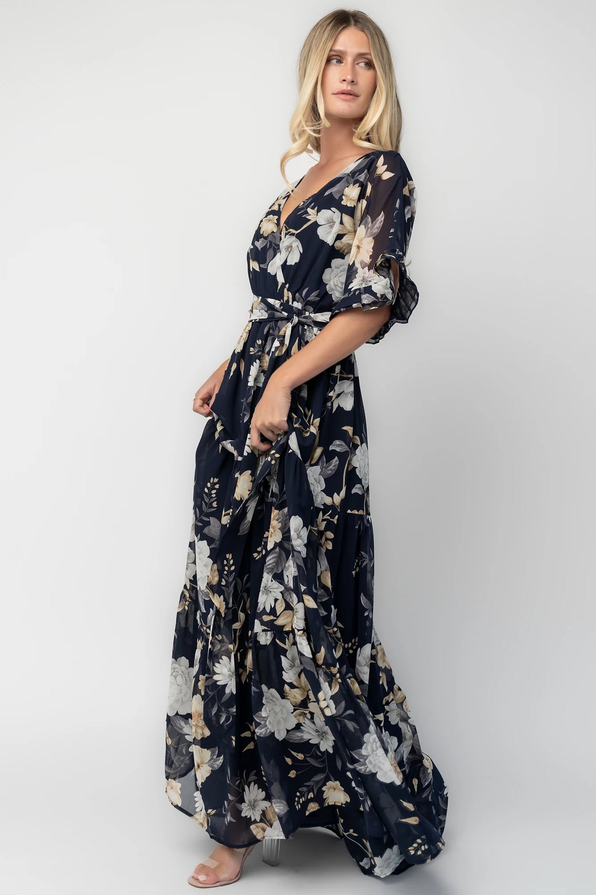 Luna Maxi Dress in Navy Floral with surplice V-neck, flutter sleeves, sash waist, and flowing tiered skirt.