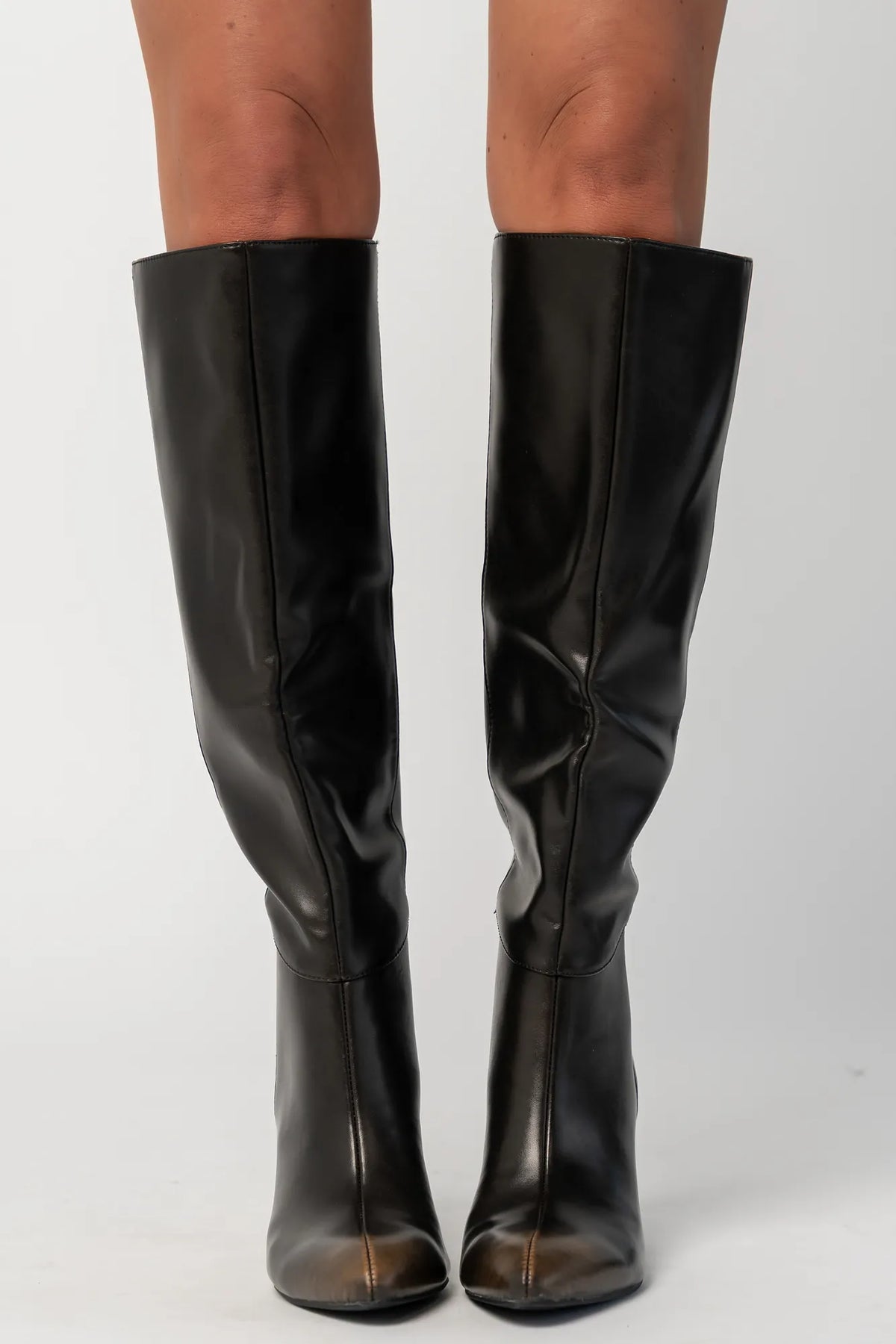 Pair of black knee-high boots featuring a pointed toe, sleek fitted shaft, and sculpted kitten heel. The streamlined silhouette and smooth finish create an elegant, versatile look that pairs effortlessly with dresses, skirts, and tailored outfits.