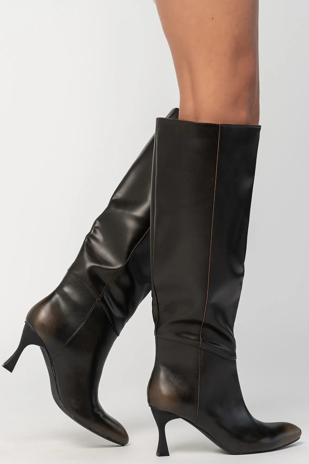 Pair of black knee-high boots featuring a pointed toe, sleek fitted shaft, and sculpted kitten heel. The streamlined silhouette and smooth finish create an elegant, versatile look that pairs effortlessly with dresses, skirts, and tailored outfits.