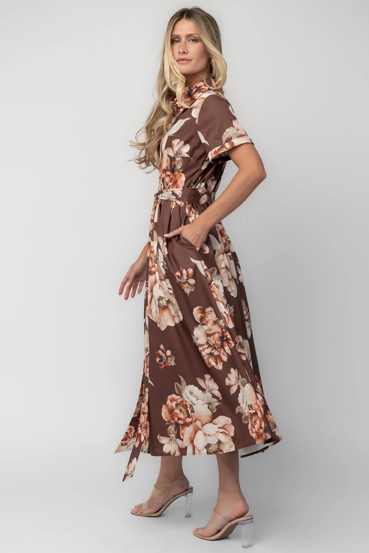 Model wearing the Blythe Midi Dress in Brown Floral featuring a collared neckline, functional button-front bodice, short rolled sleeves, and a removable waist tie.