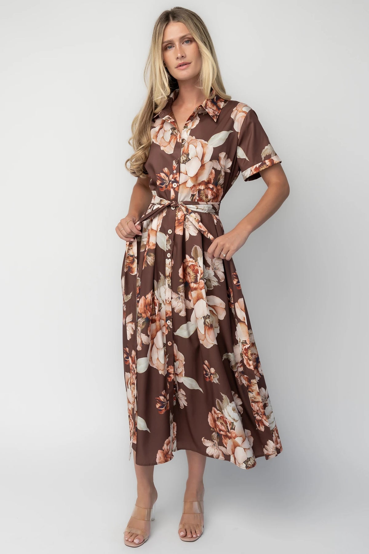 Model wearing the Blythe Midi Dress in Brown Floral featuring a collared neckline, functional button-front bodice, short rolled sleeves, and a removable waist tie.