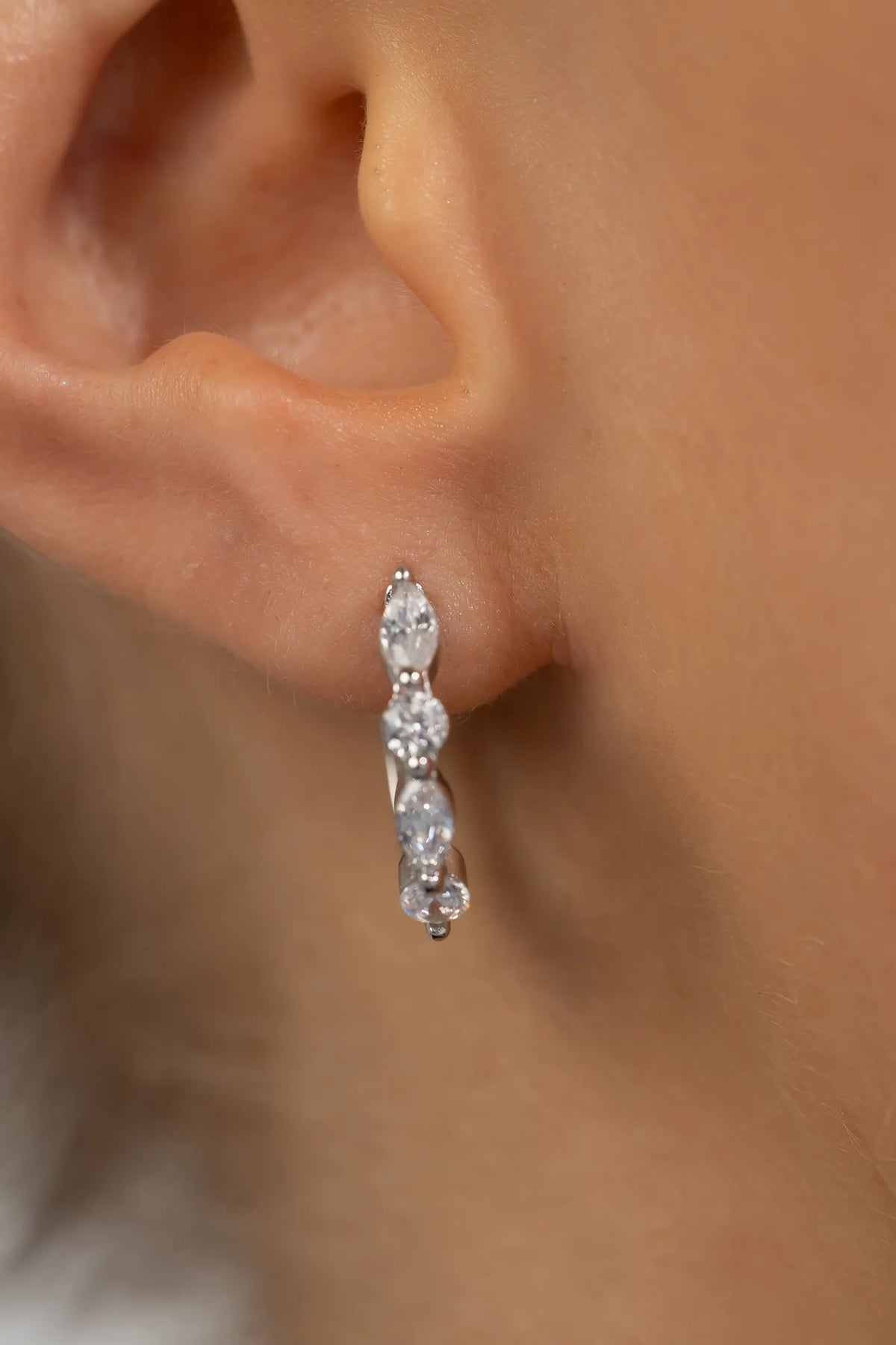 Silver hoop earrings adorned with clear crystal stones in mixed round and marquise shapes.